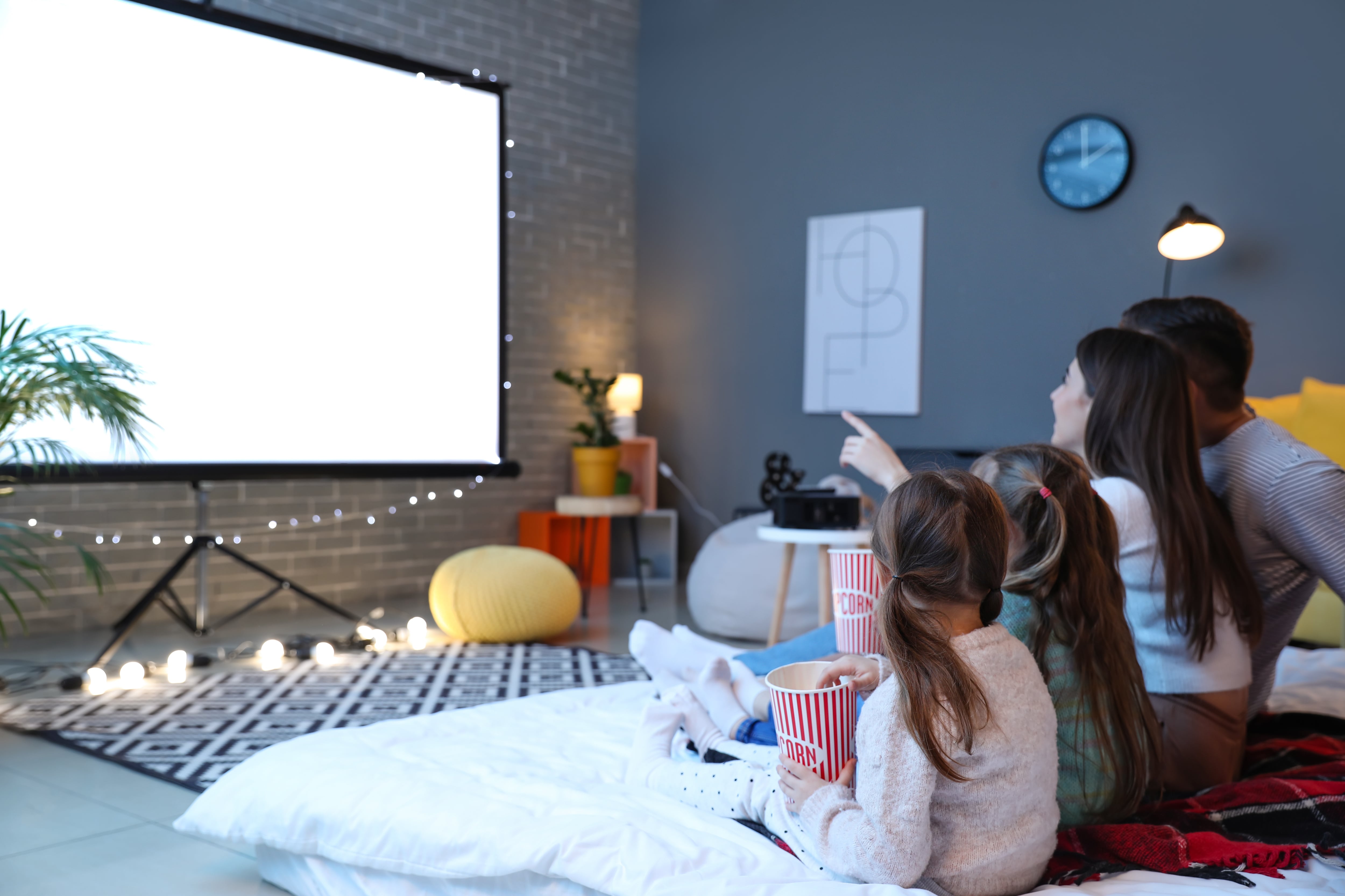 A young family watching a movie on a projector screen