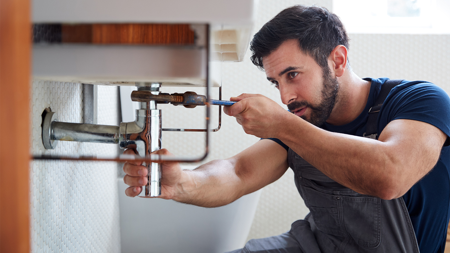 repairman working on bathroom sink 