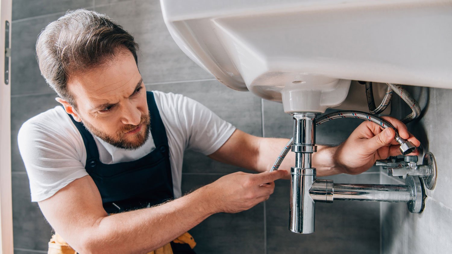 A plumber repairing a bathroom sink pipe