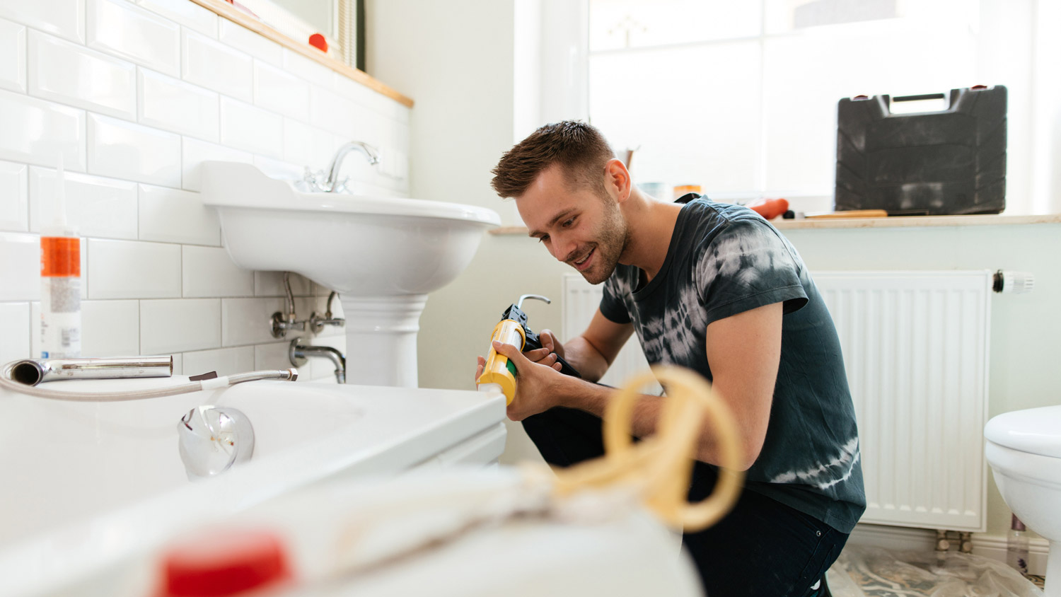 A plumber applying silicone to a bathtub