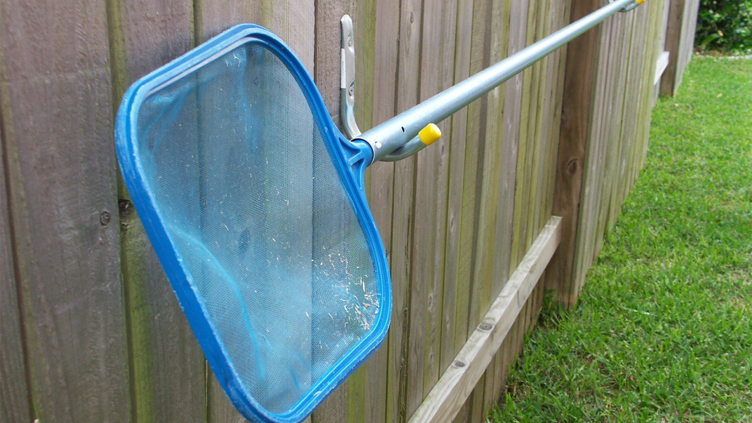 pool skimmer hanging on fence