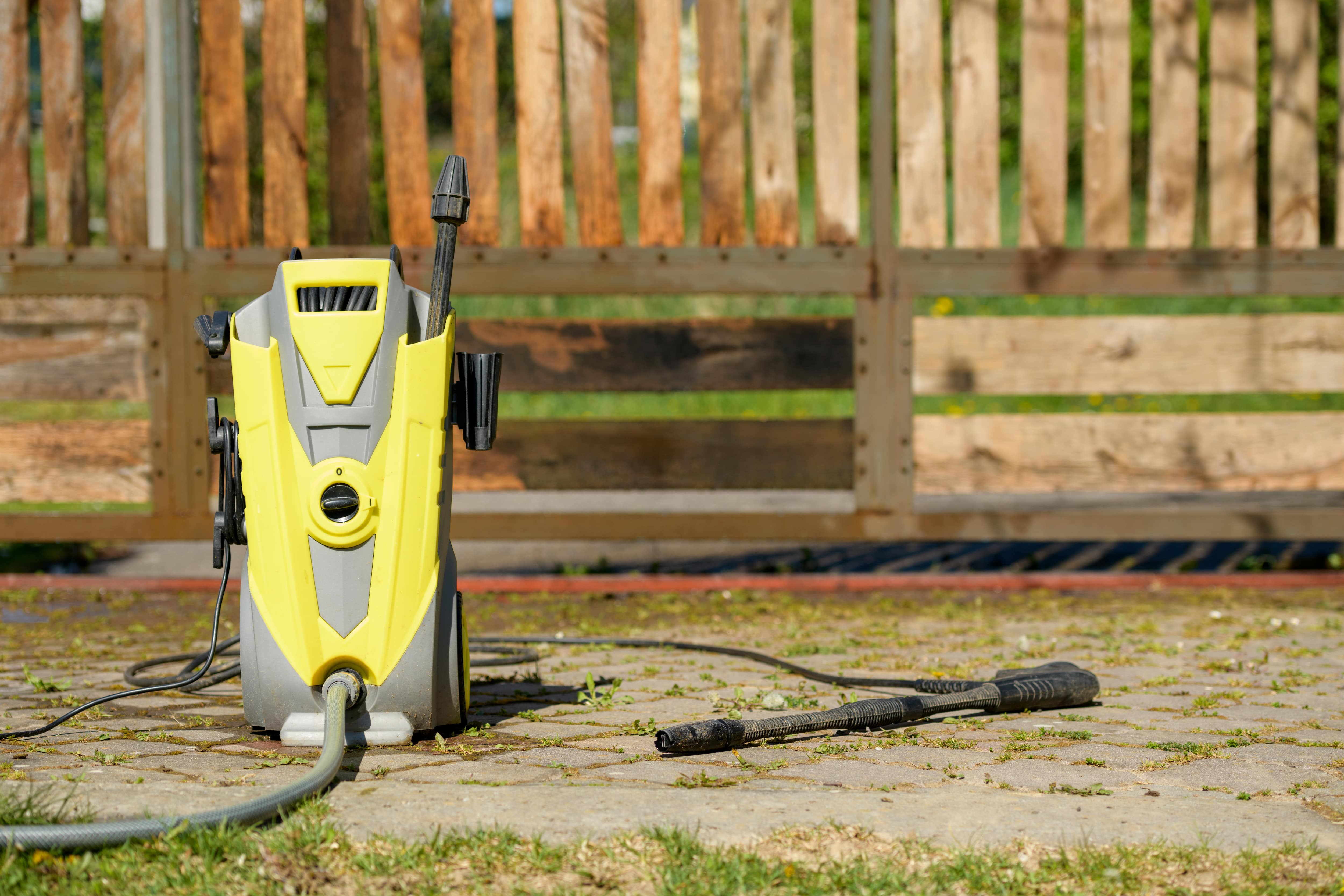 Pressure washer in front of wooden fence