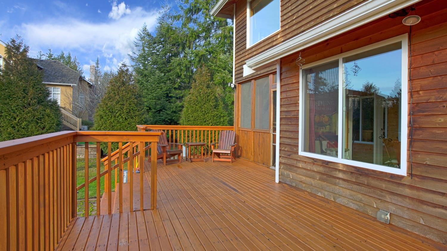A pressure-treated pine deck in the backyard of a wooden house