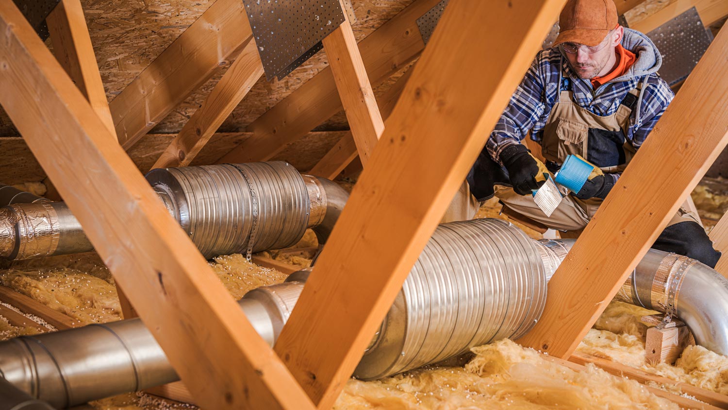 A professional installing air ventilation tubes in an attic