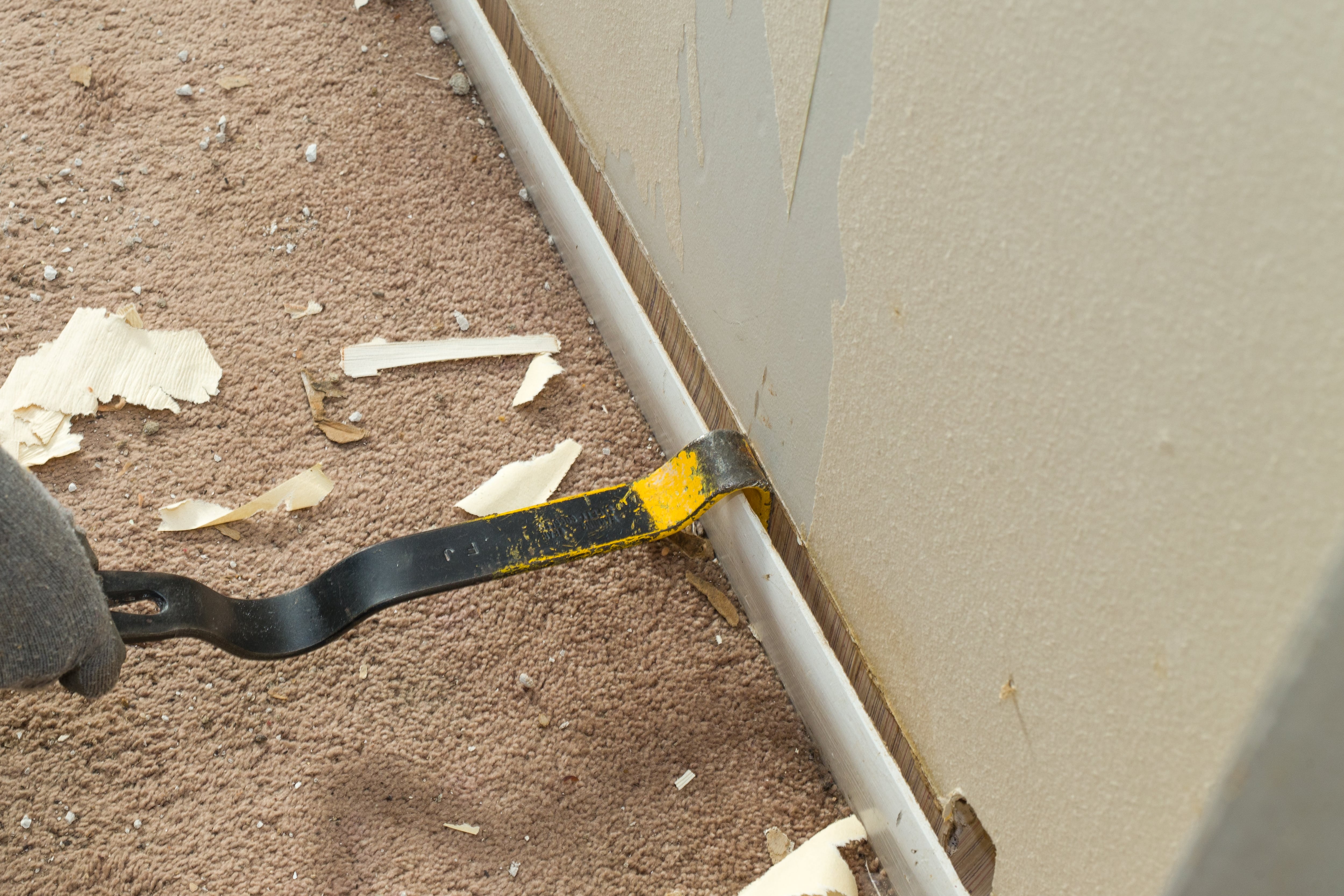 Pulling away old baseboards with a pry bar