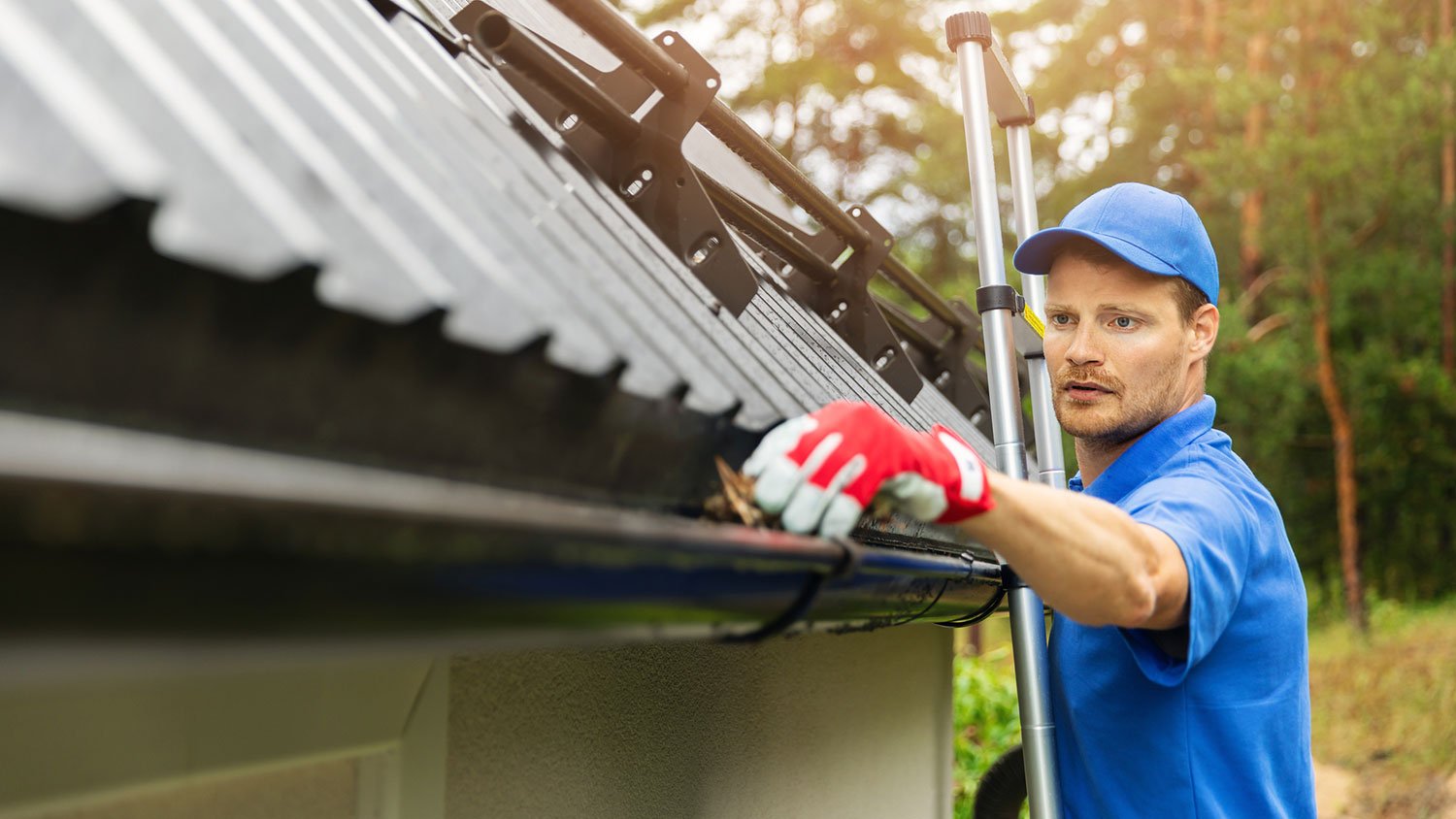 Worker wearing uniform cleaning house gutters