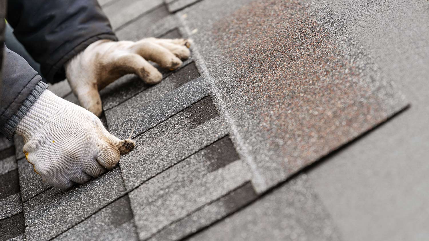 Worker installing shingles on roof