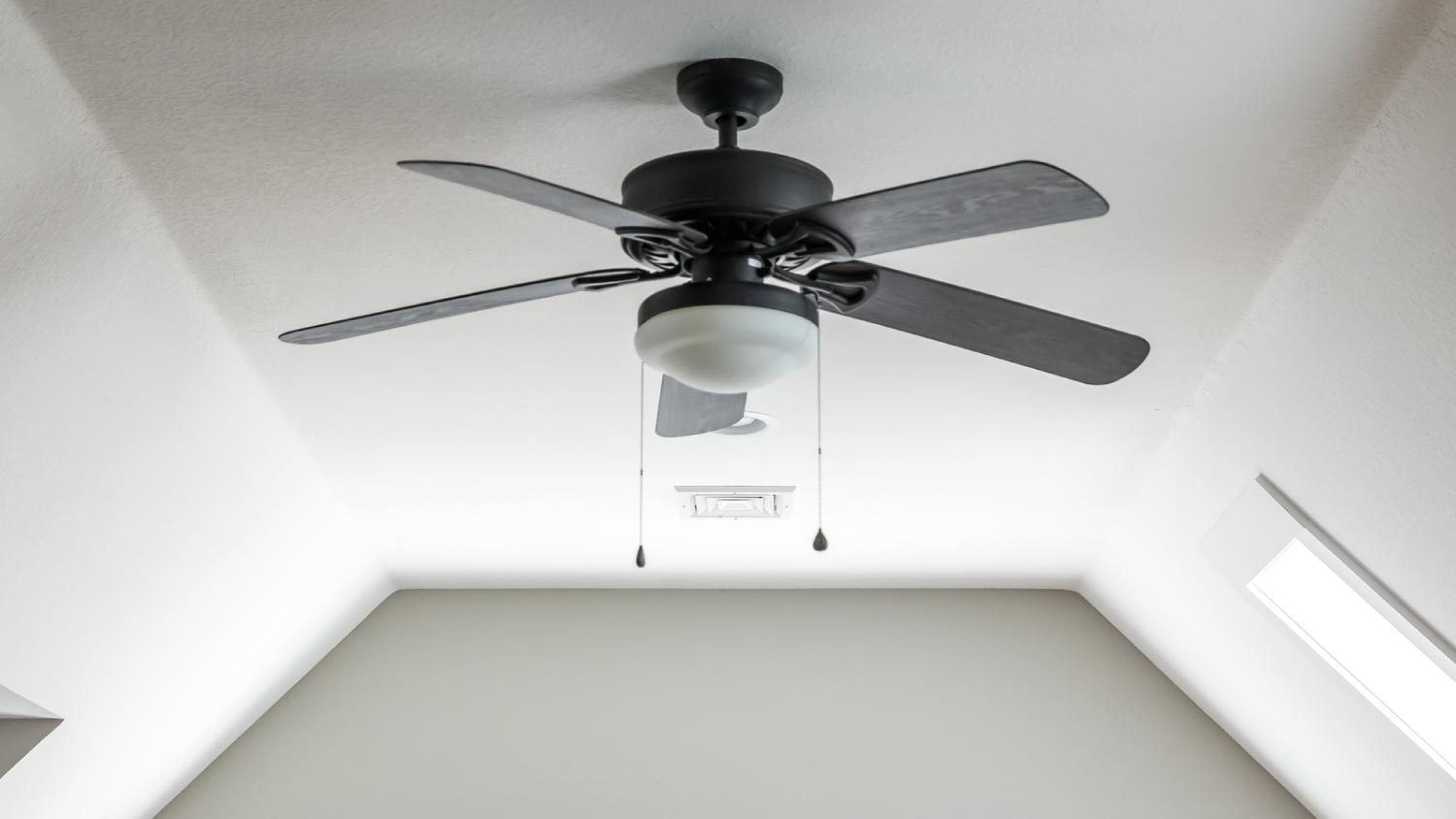 A room with a dark wood ceiling fan