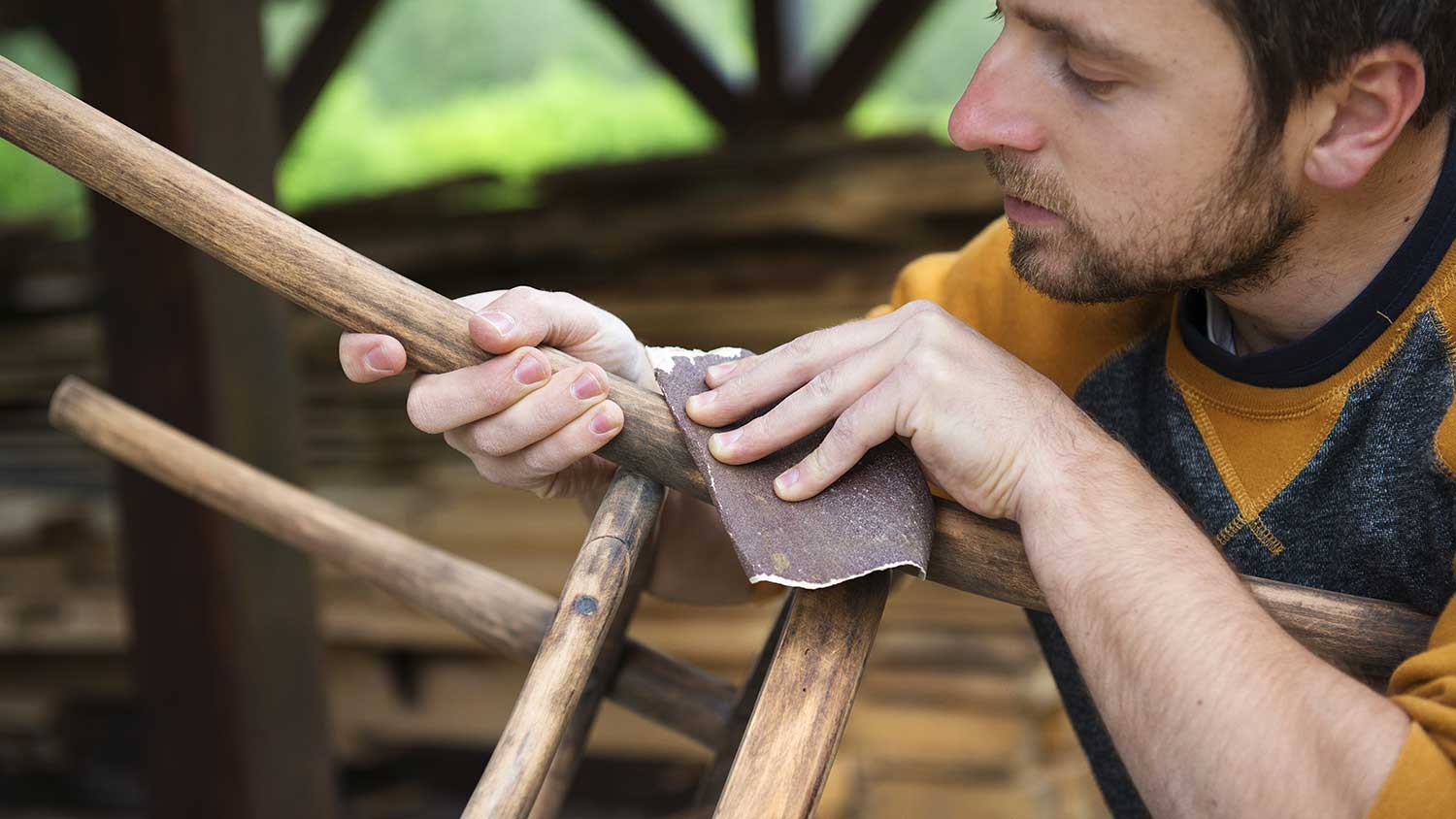 Man using sanding paper to restore a chair