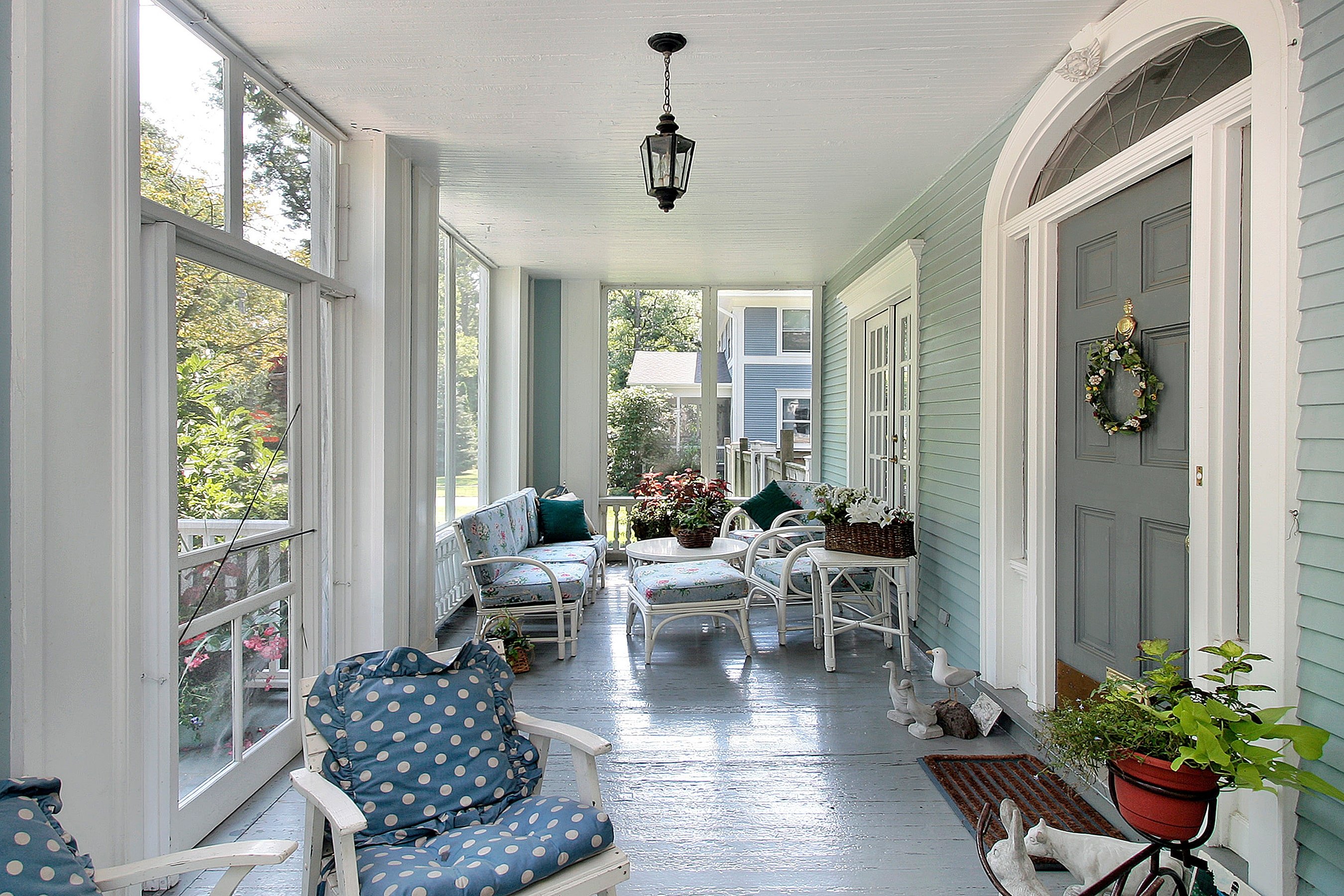 A large screened-in front porch with patio seating and plants