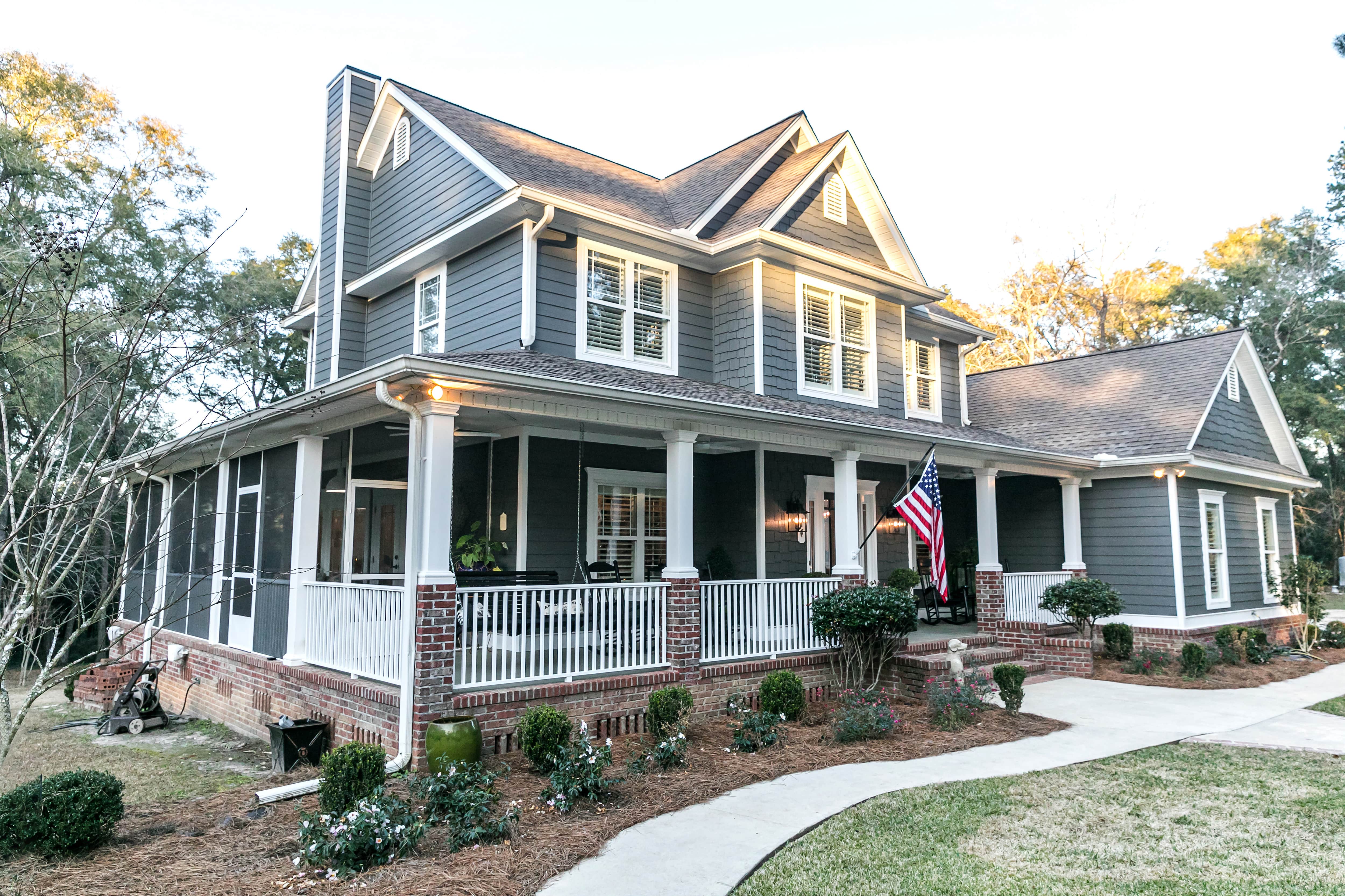 A large farmhouse with a wraparound porch that is partially screened-in