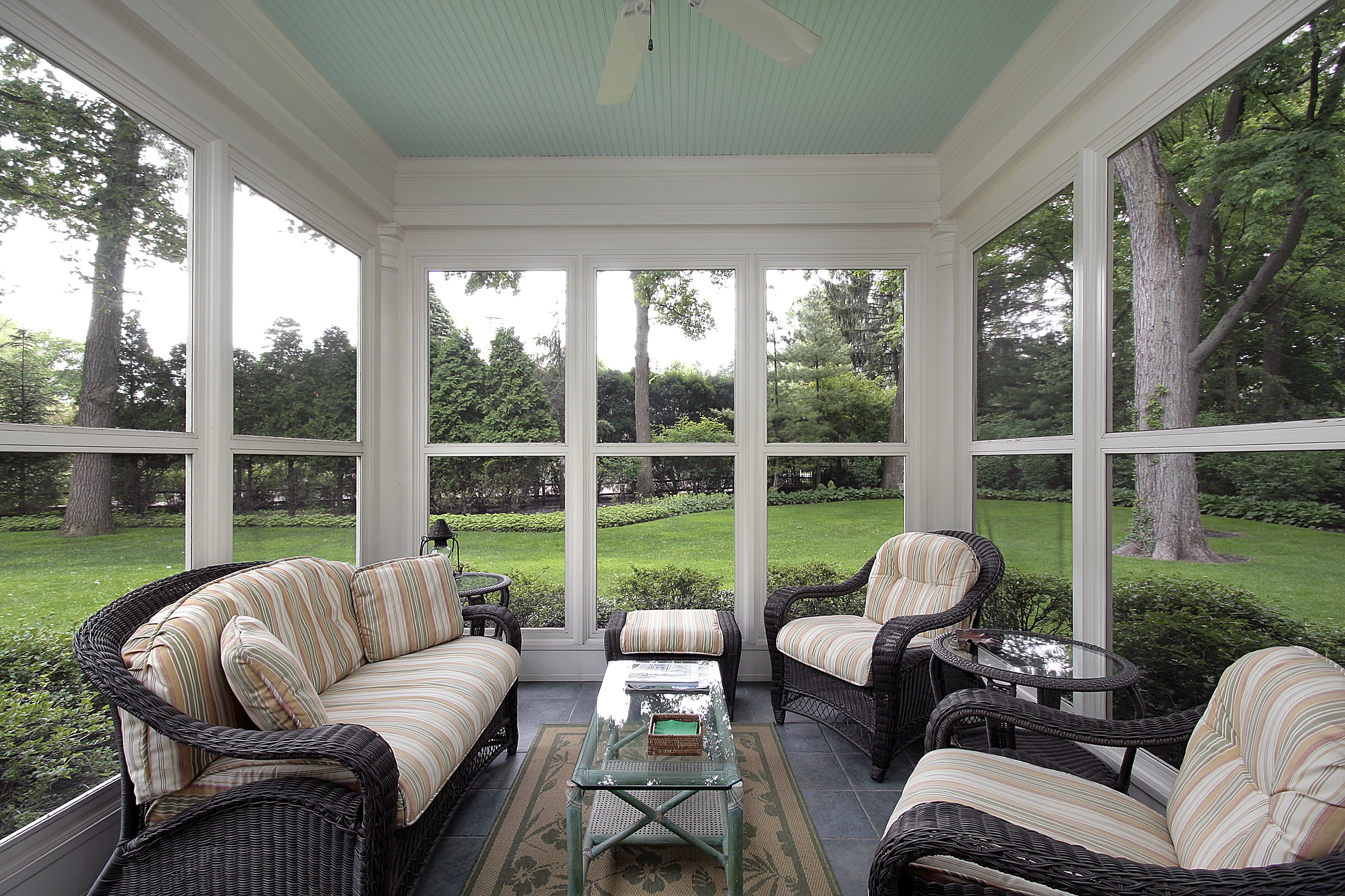 A screened-in porch with light blue shiplap ceiling