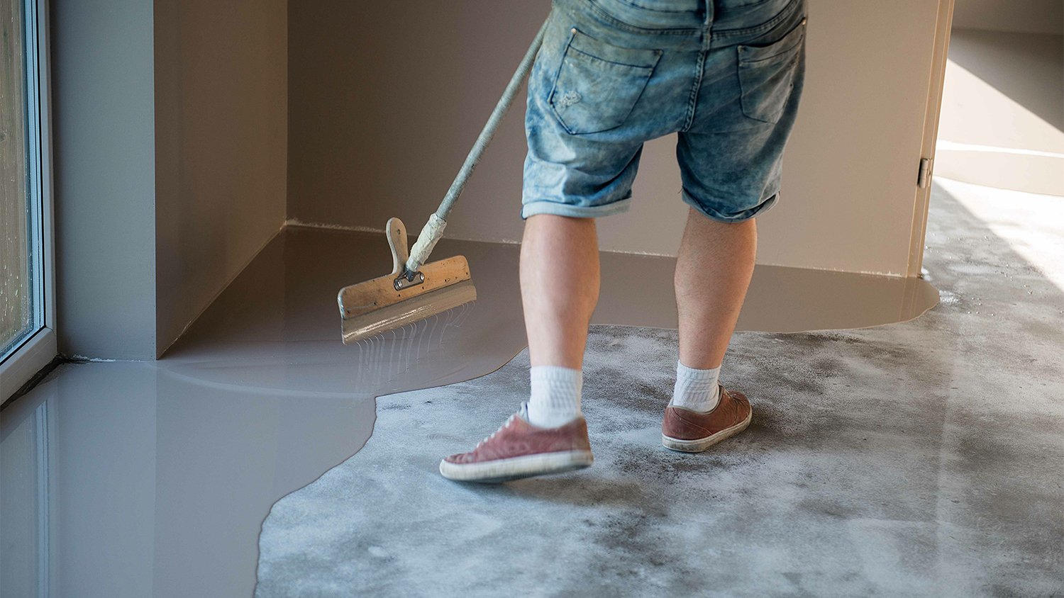 man using epoxy on cement basement floor
