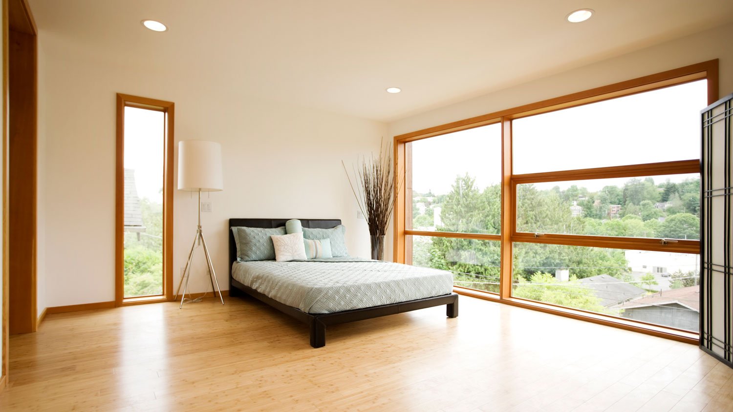 A spacious bedroom with large windows and bamboo flooring