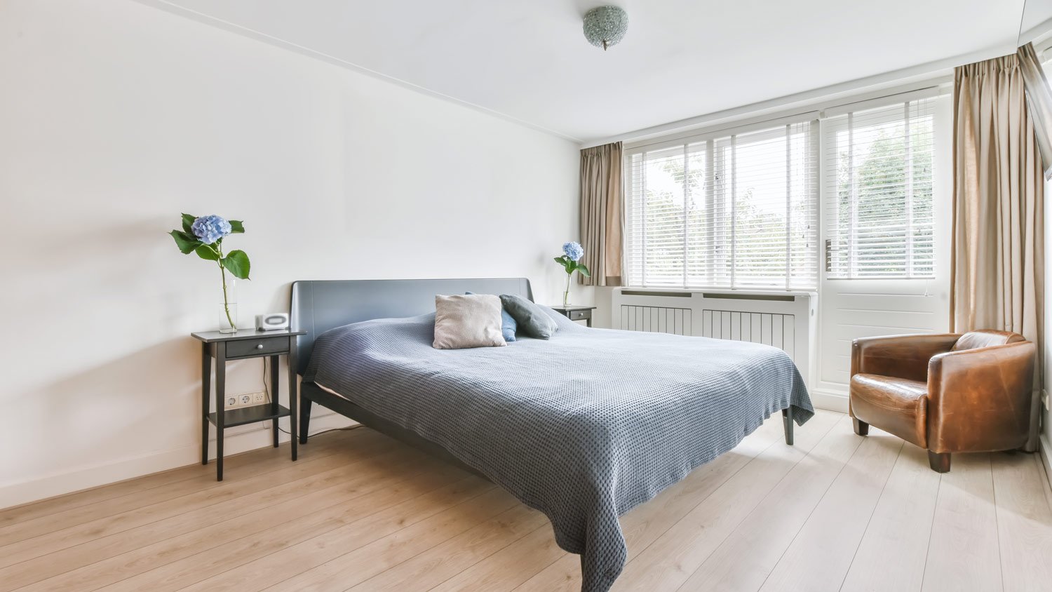 A spacious bedroom with an enlarged window overlooking trees
