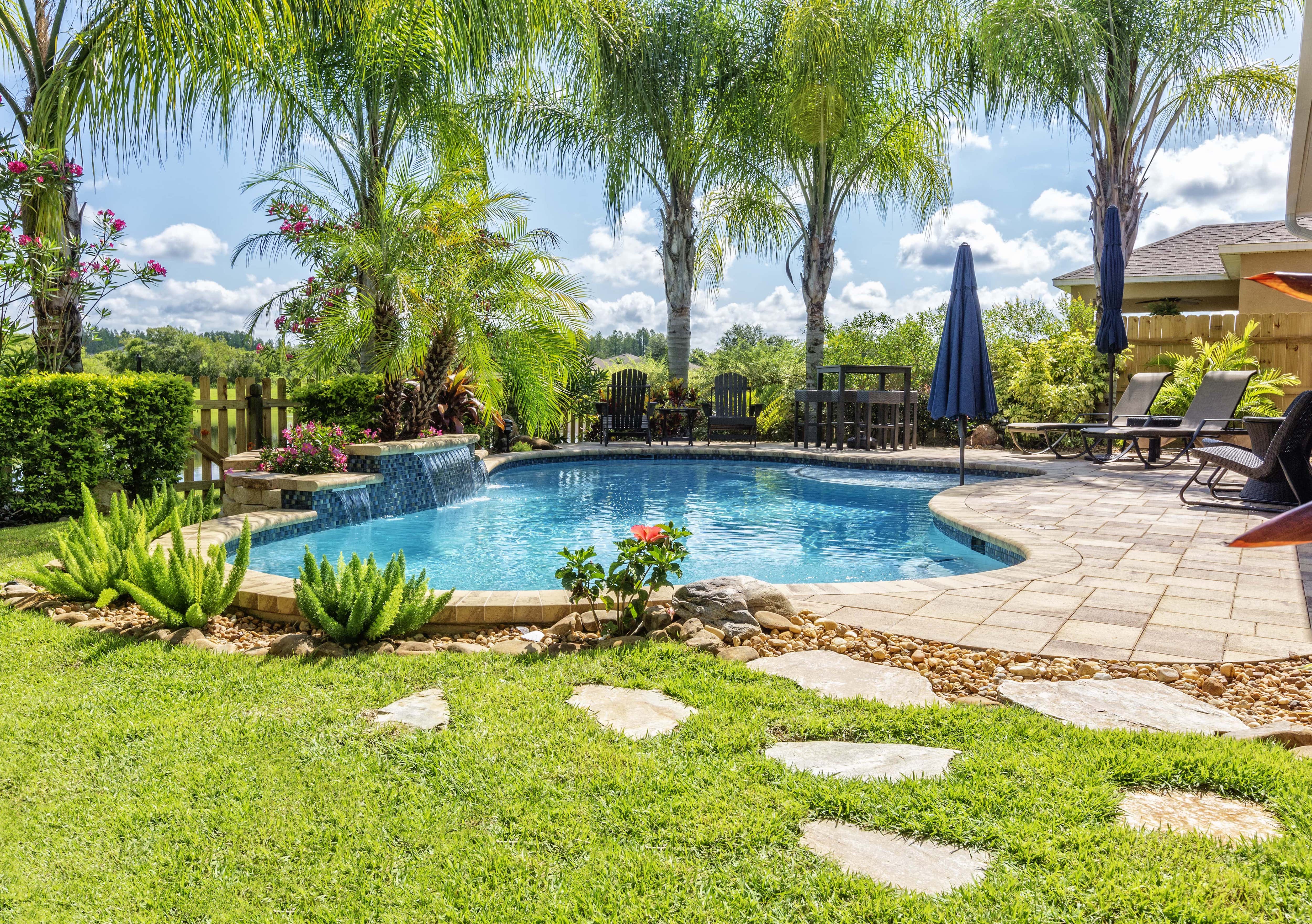 An in-ground backyard pool with stepping stones leading up to the patio