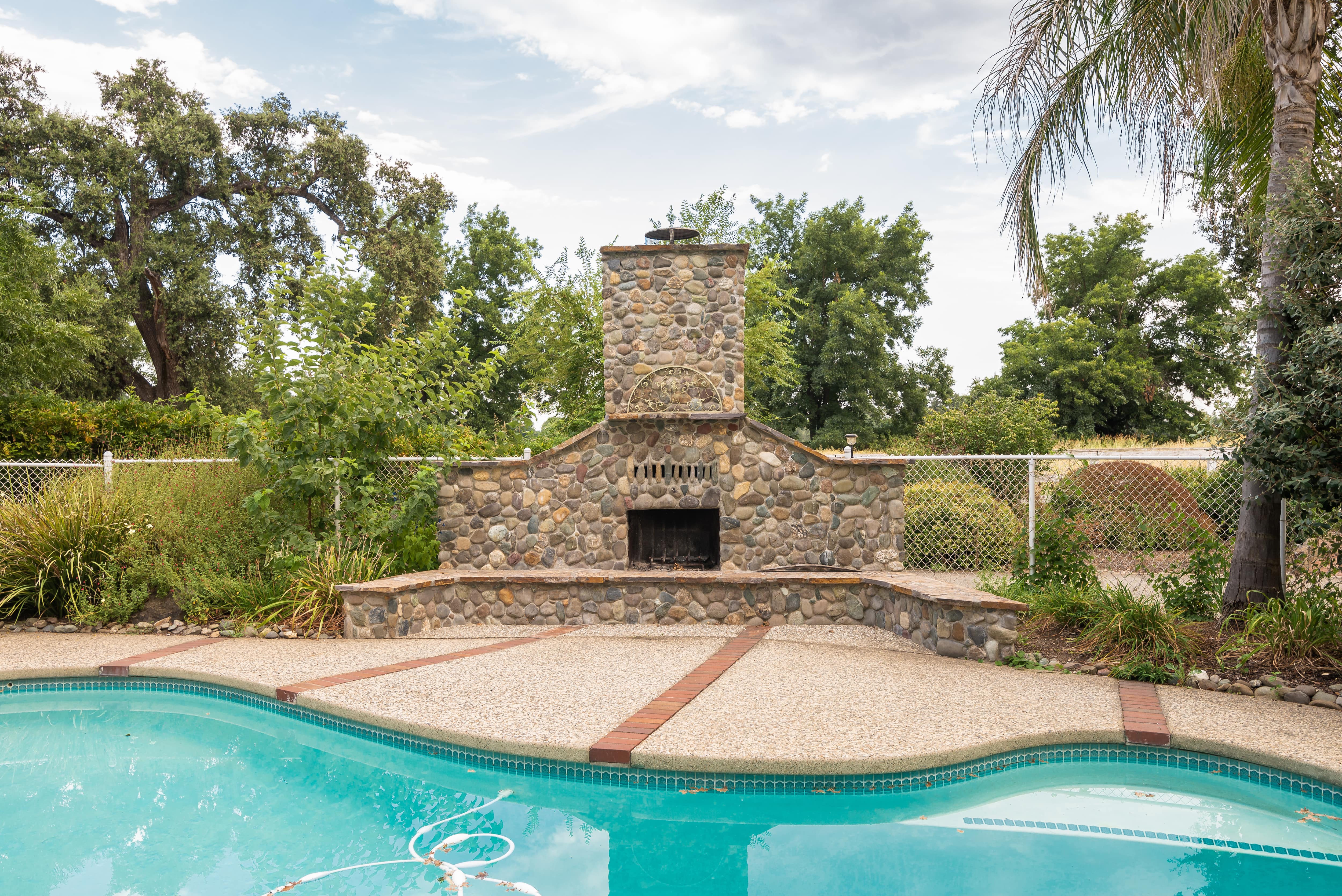 Fireplace next to a pool in a backyard