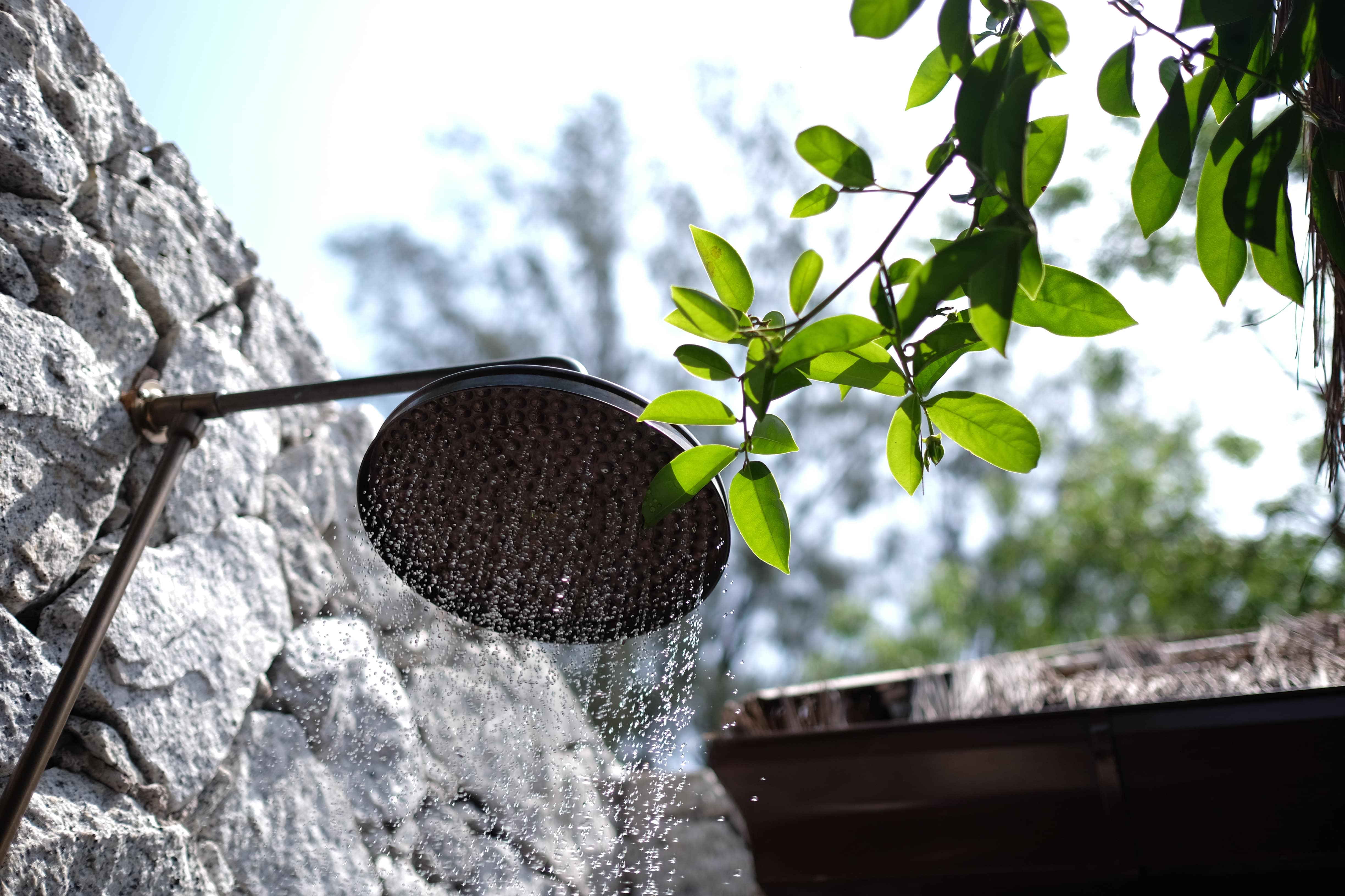 A rainfall showerhead built into an outdoor stone wall