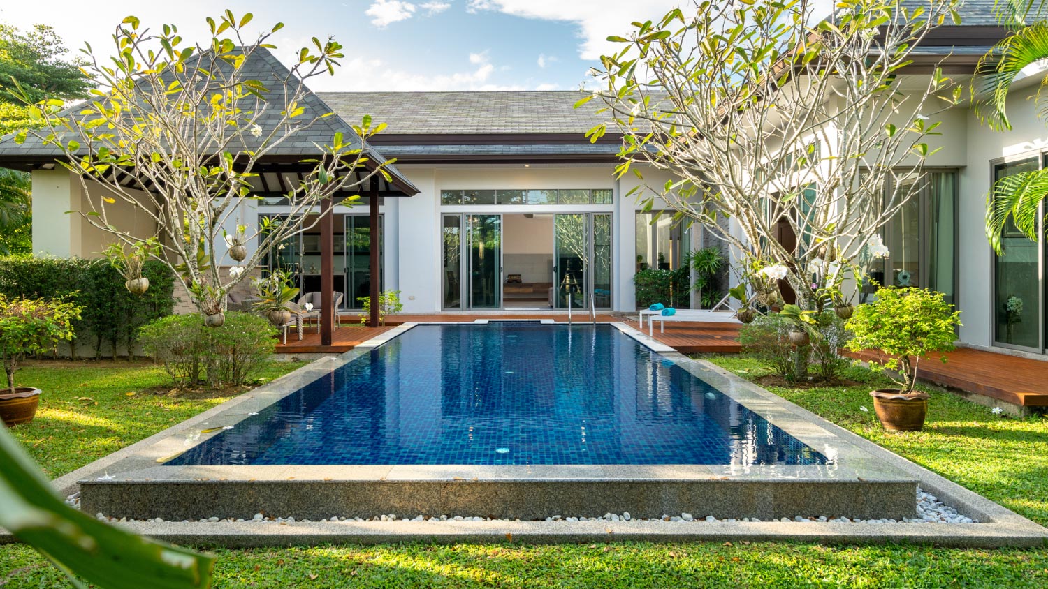 A swimming pool and pavilion with green garden