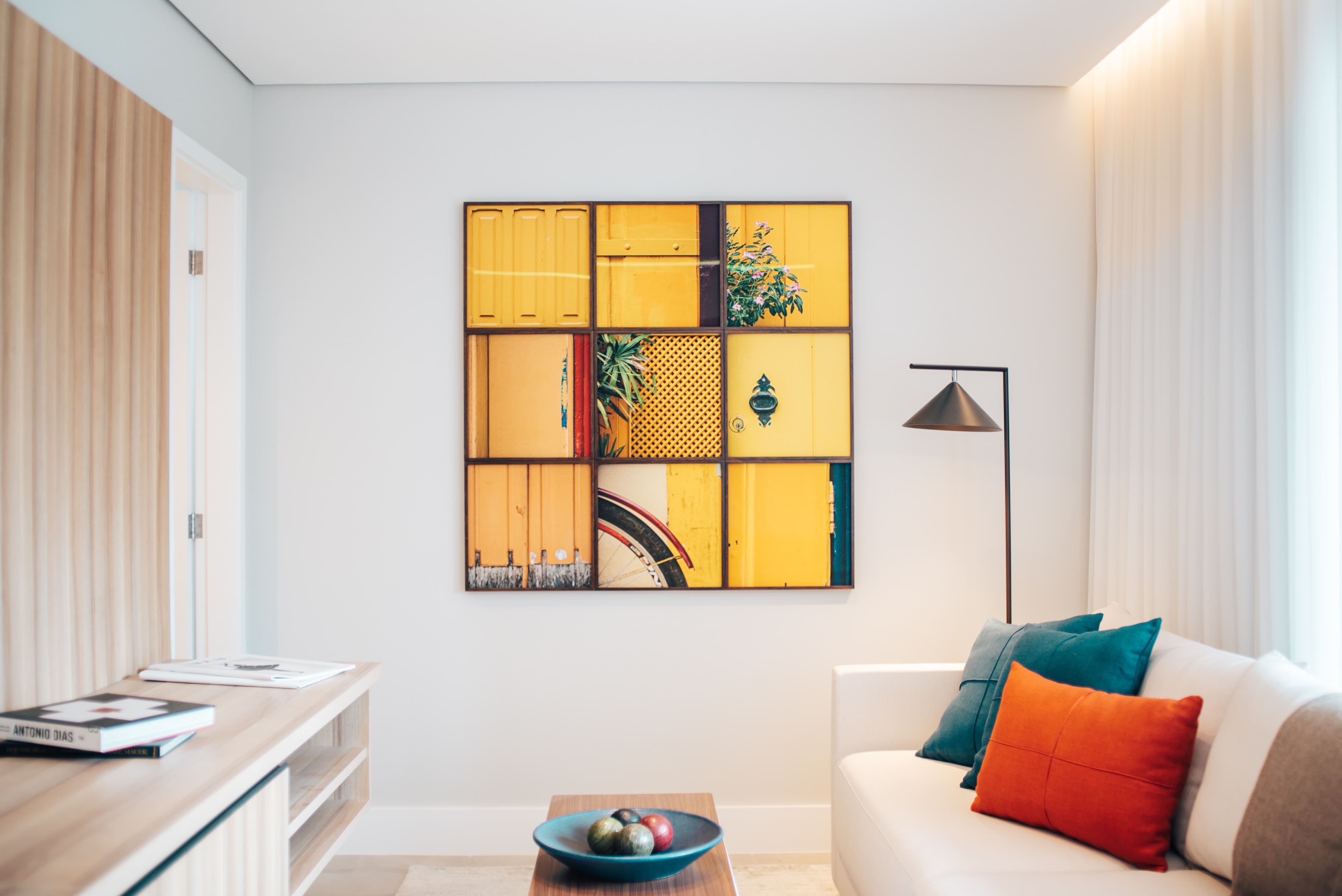 White sofa with throw pillows and cube-shaped gallery wall featuring 9 photos of yellow doors