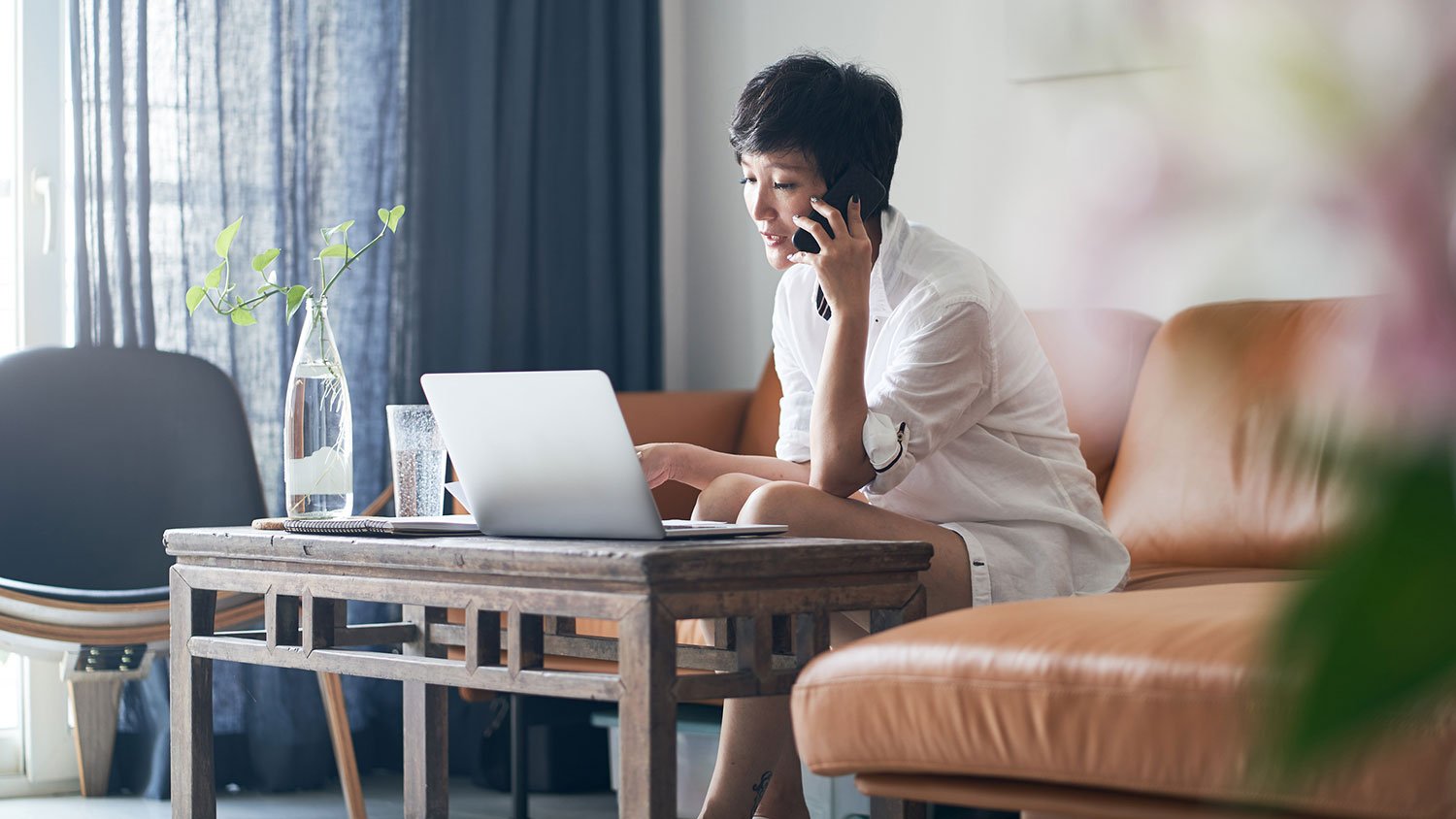 Woman talking on the phone and using laptop at home