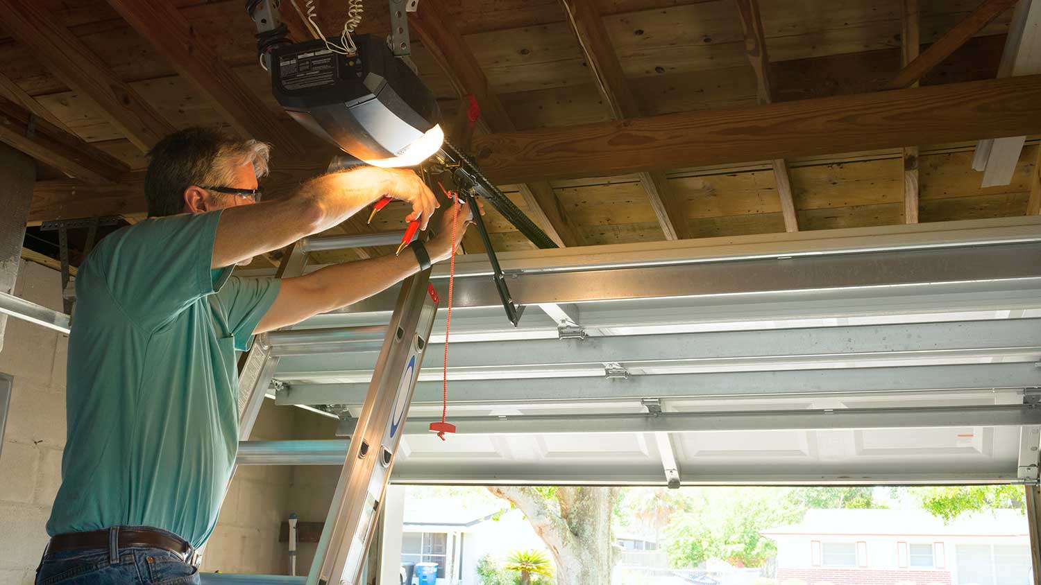 Technician on a ladder repairing residential garage door