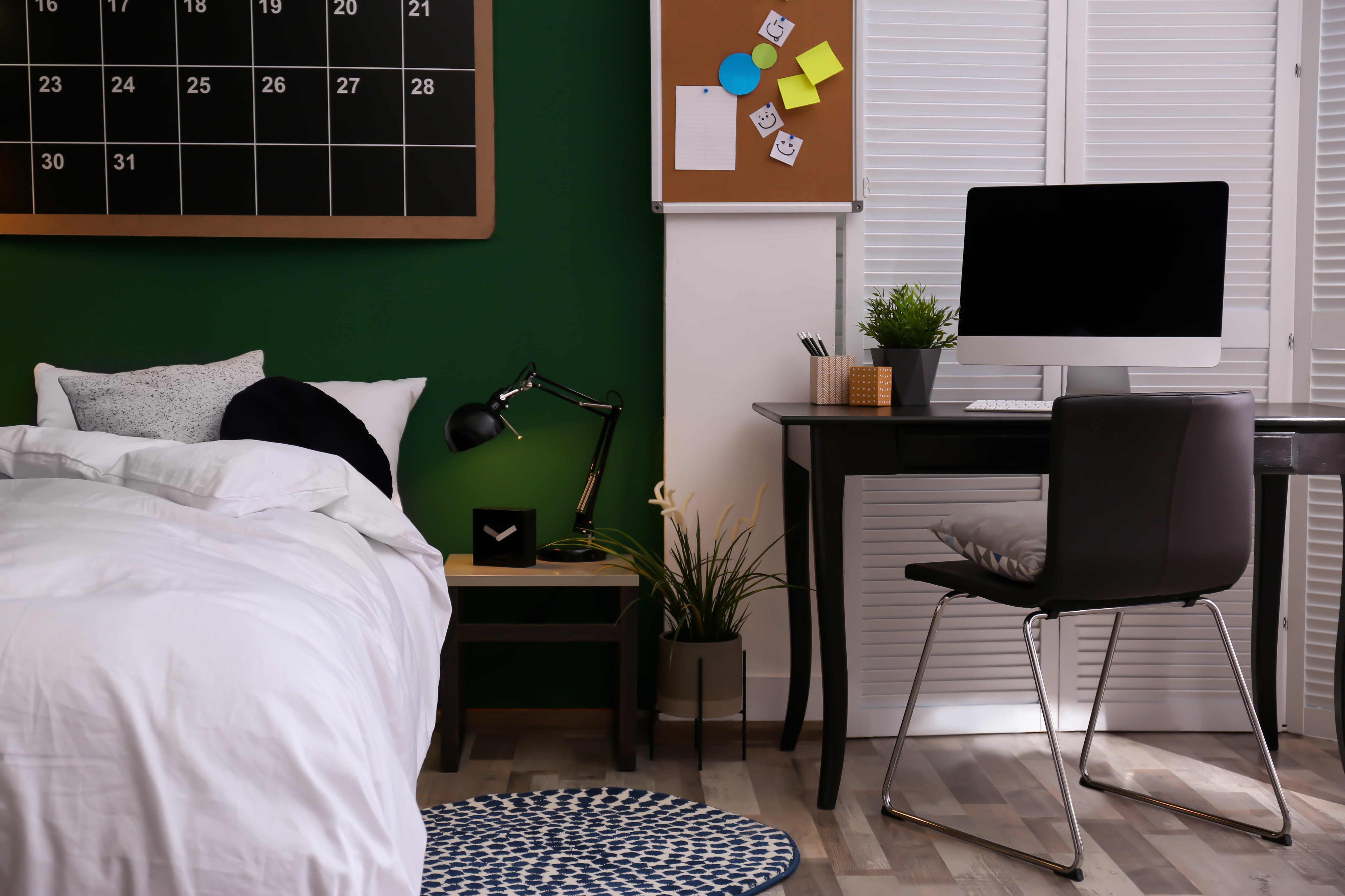 Teen room with desk and comfortable bed against green wall