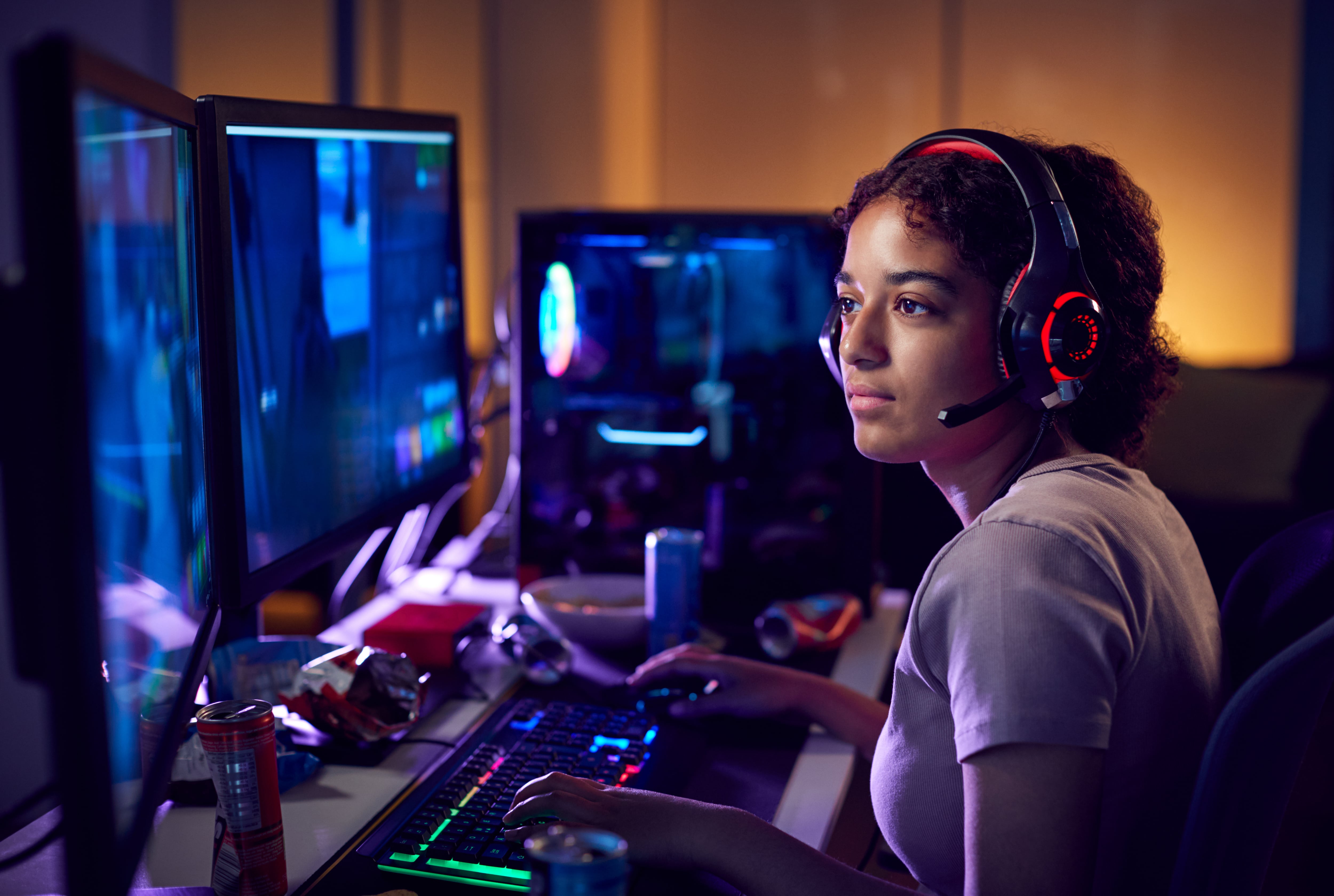 Teen gamer using dual computer screens in her bedroom