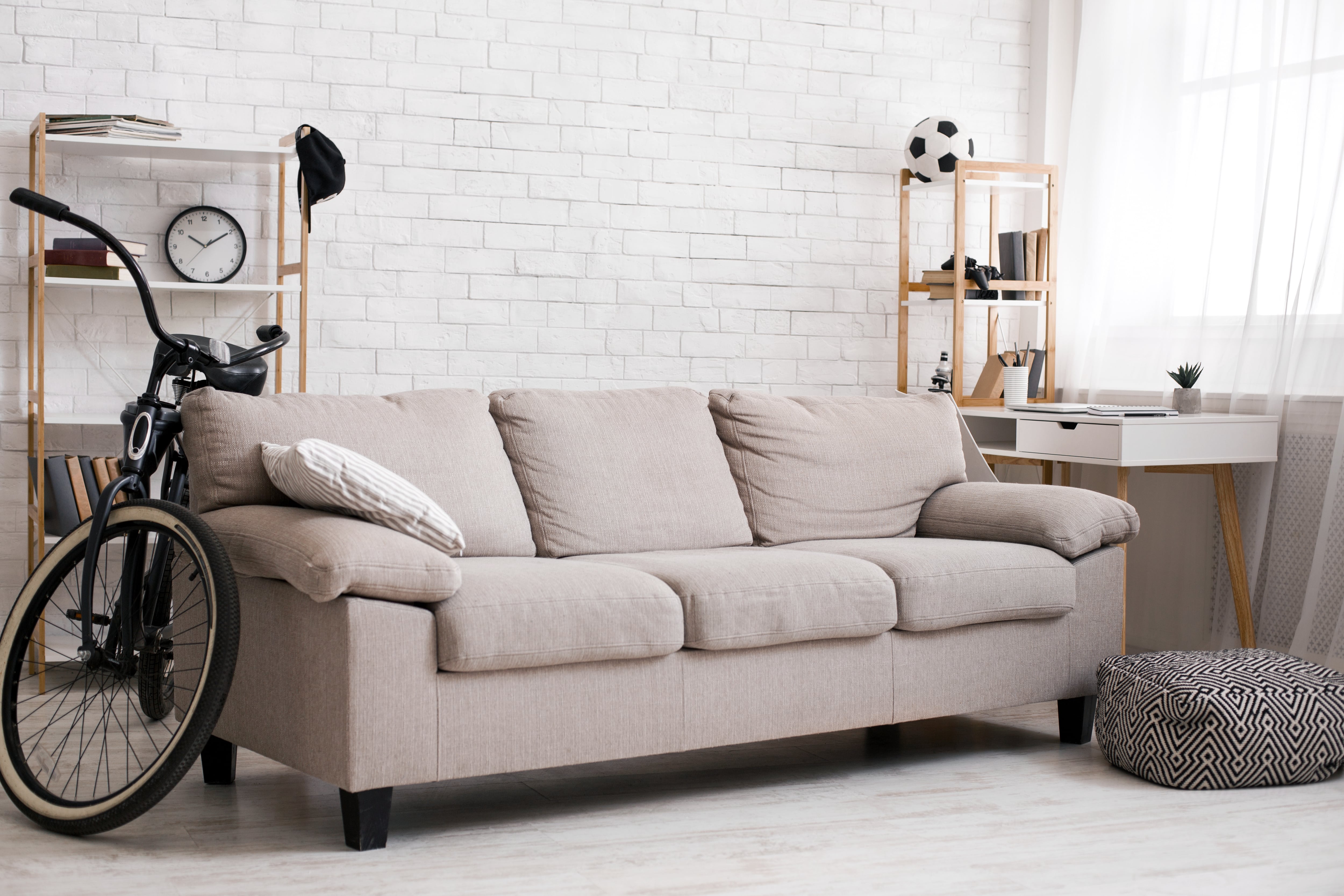 minimalist teen bedroom with grey sofa and bicycle