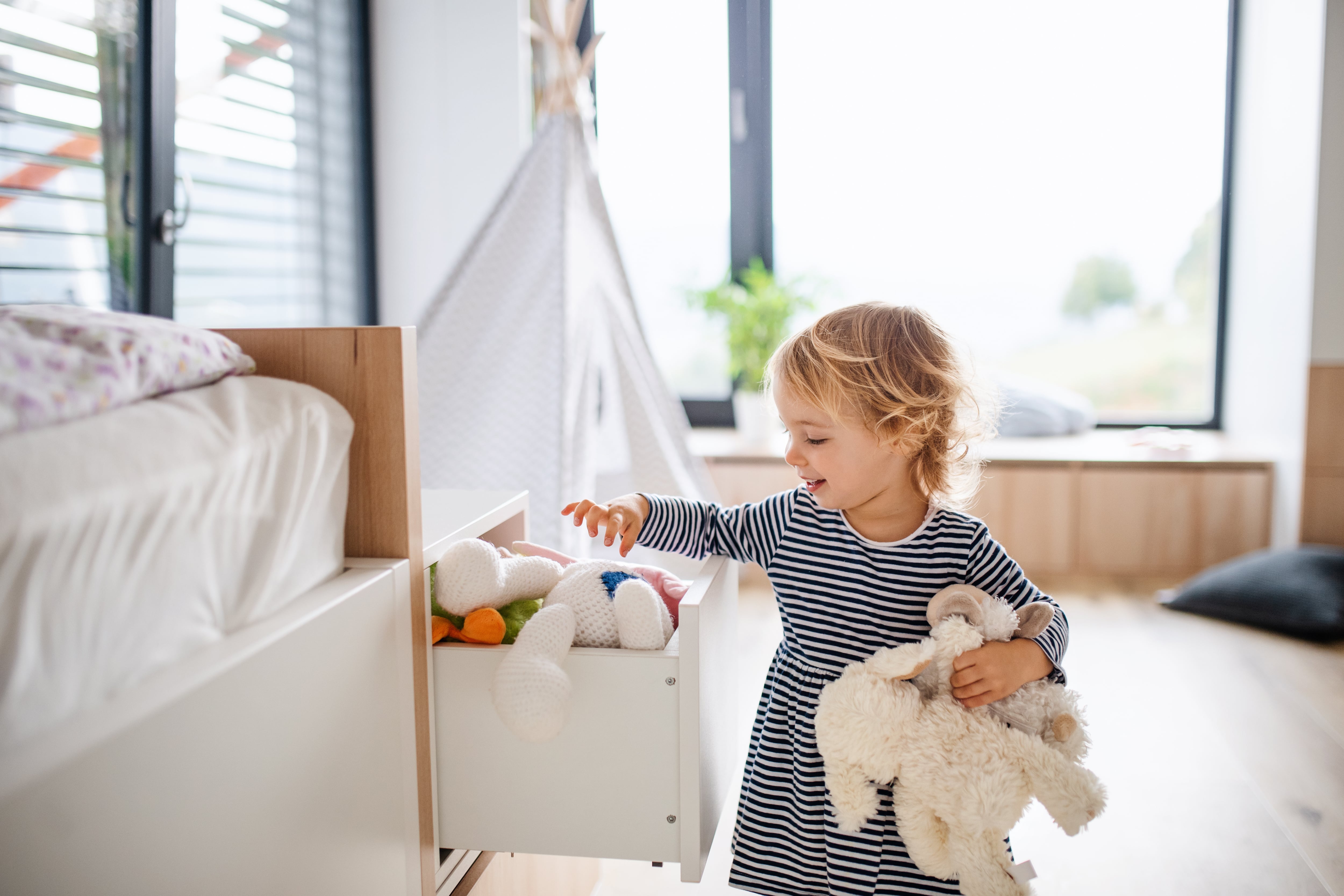 A little girl going through storage drawers in a playroom