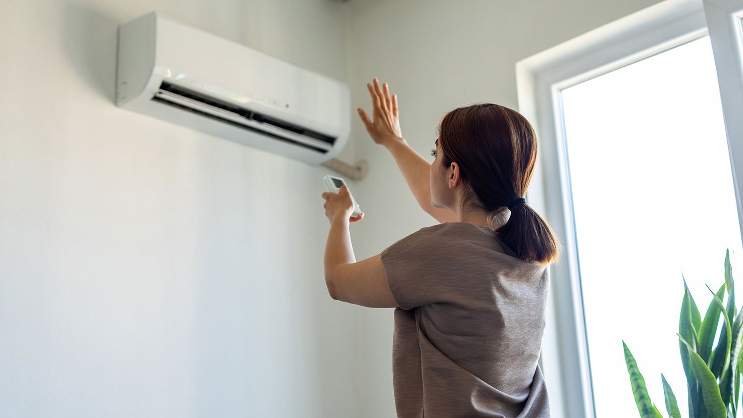 Woman using remote control to turn on ac unit