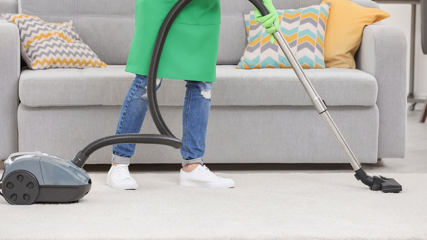 Woman vacuuming white carpet in living room