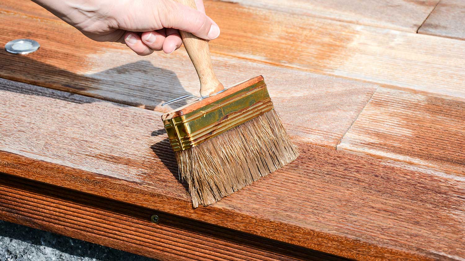Applying varnish to a wood deck with a brush