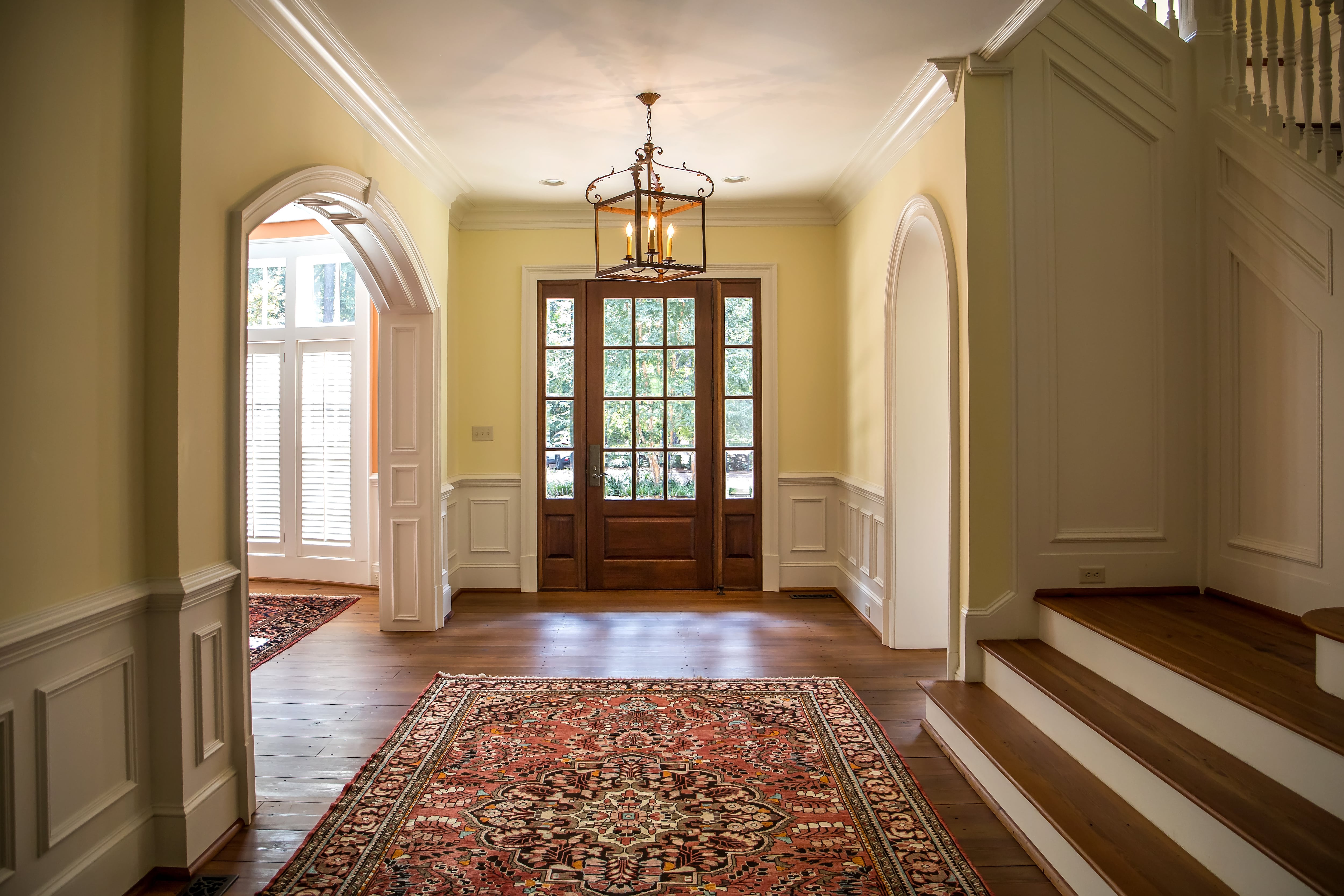 Grand entryway with traditional white wainscoting walls opening up to other rooms in the home