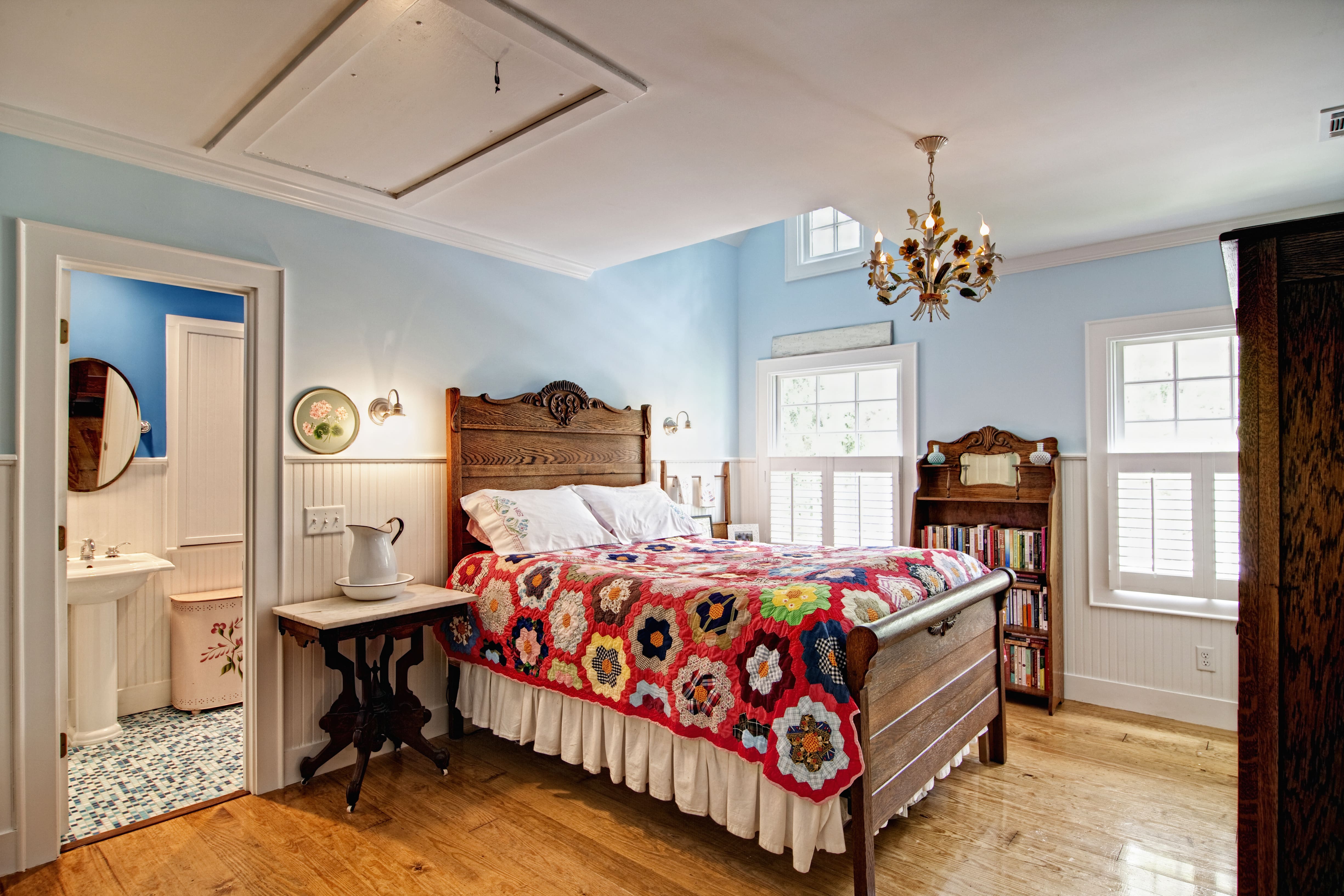 Bedroom suite with quilted bedspread and beadboard wainscotting along walls