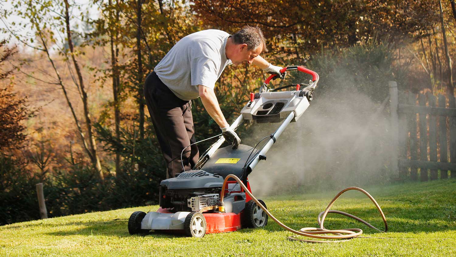 Man washing lawn mower in his yard