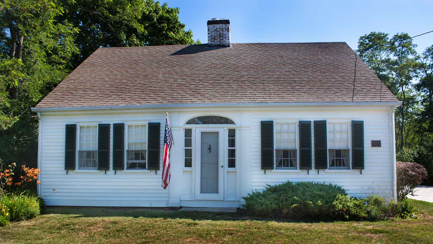 White cape cod house with green shutters