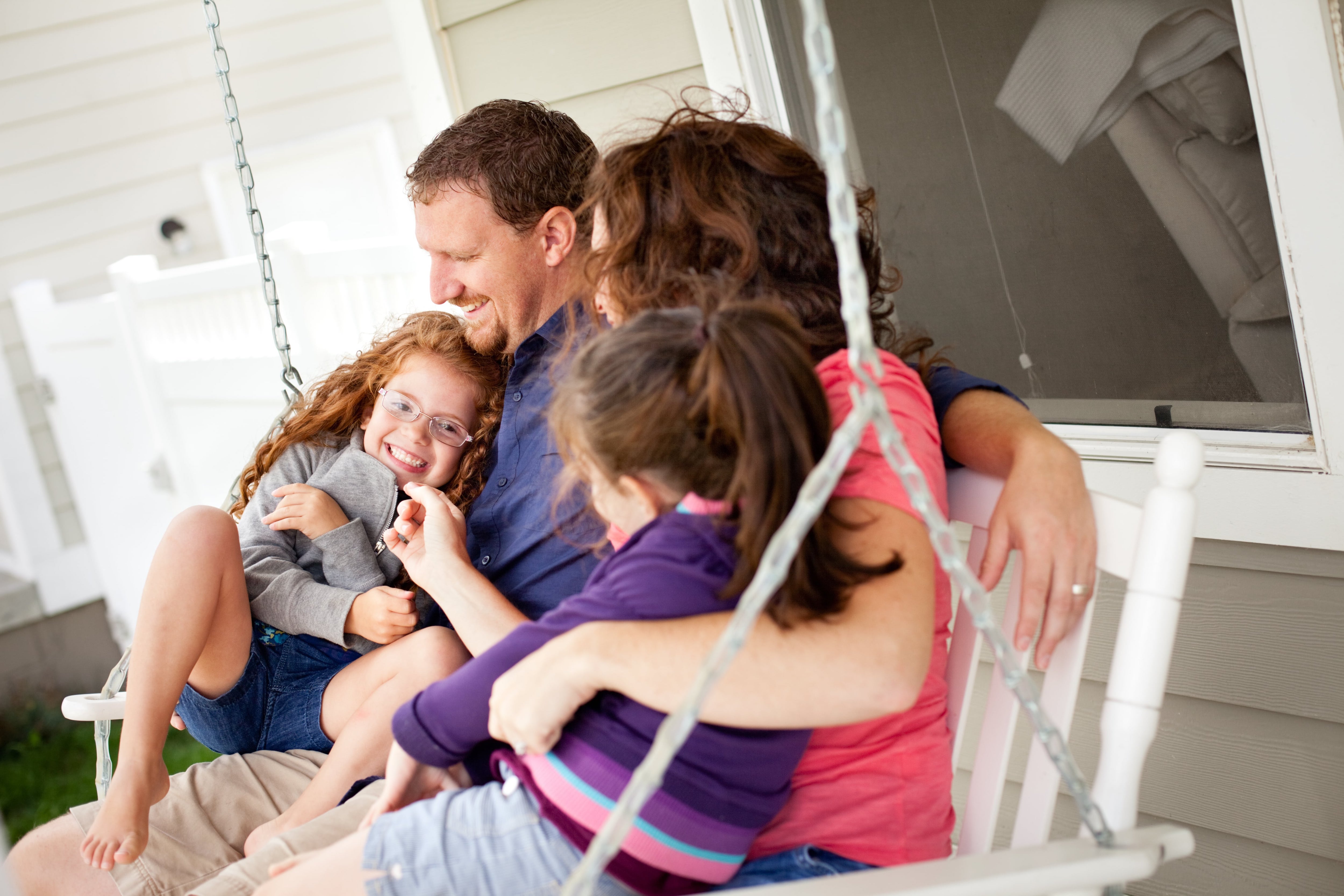 Family sitting together on a white porch swing