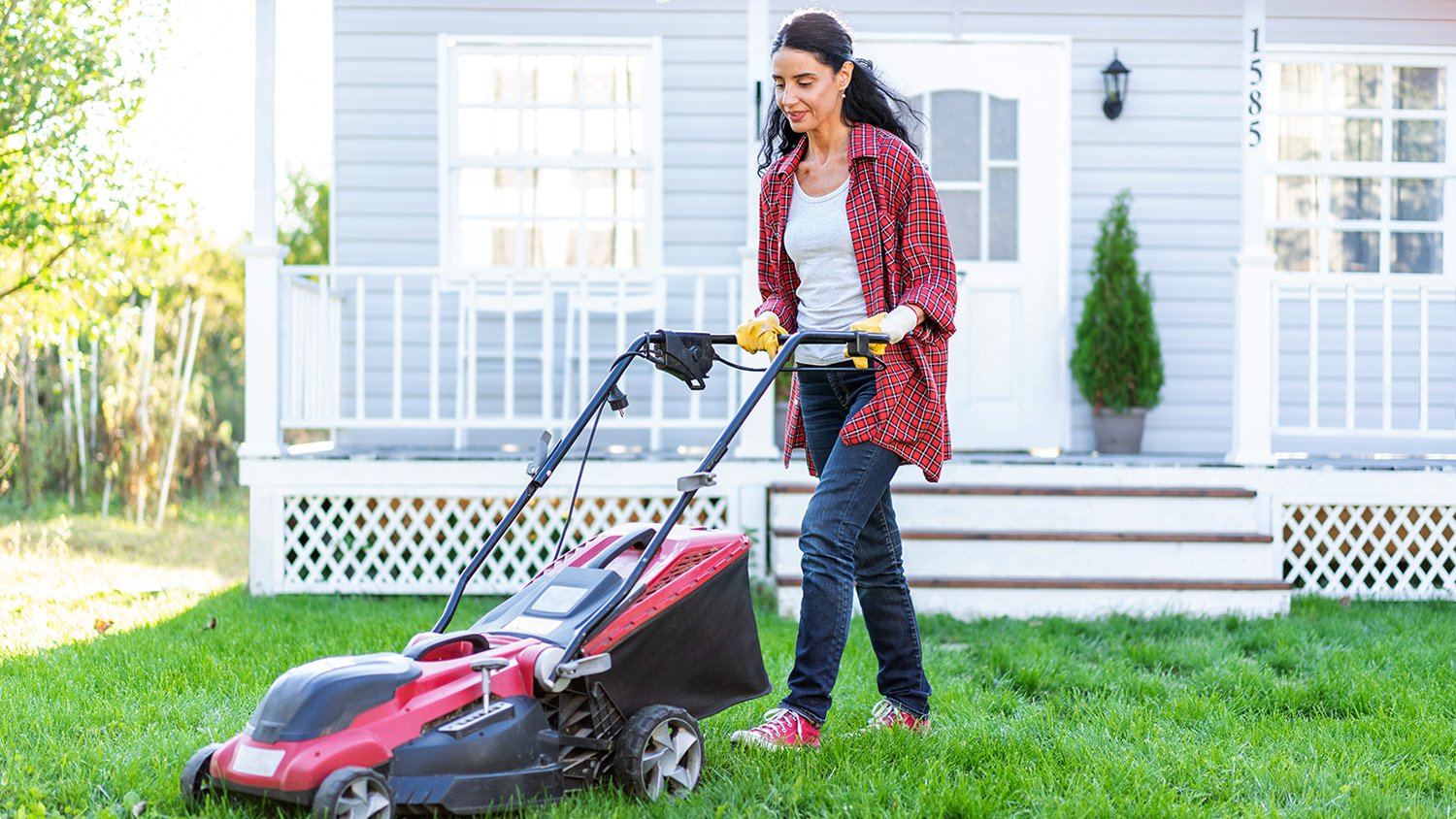 woman mowing lawn in front yard