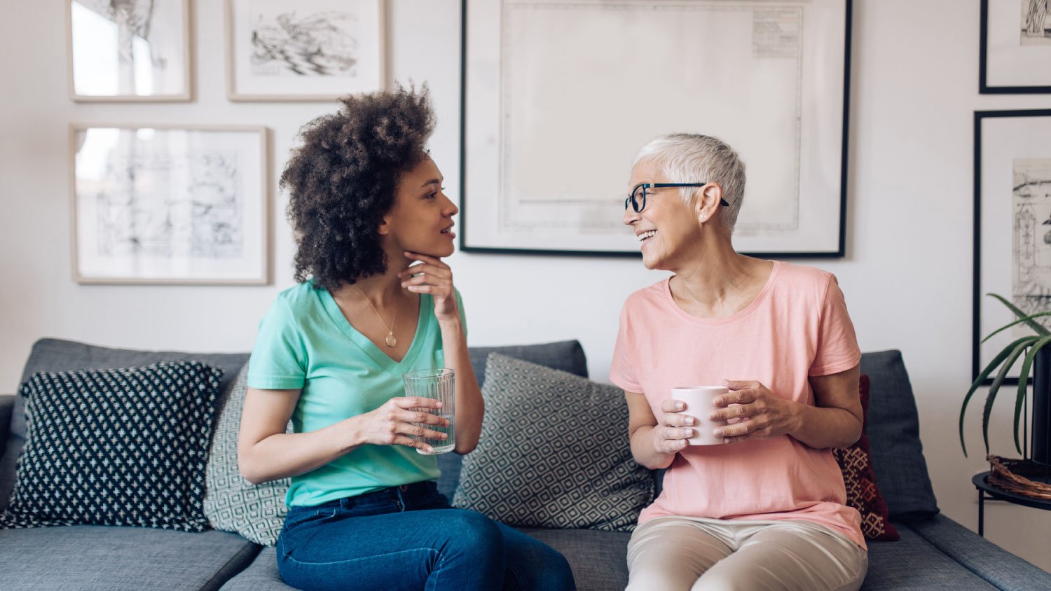 two women sitting on a couch talking with coffee