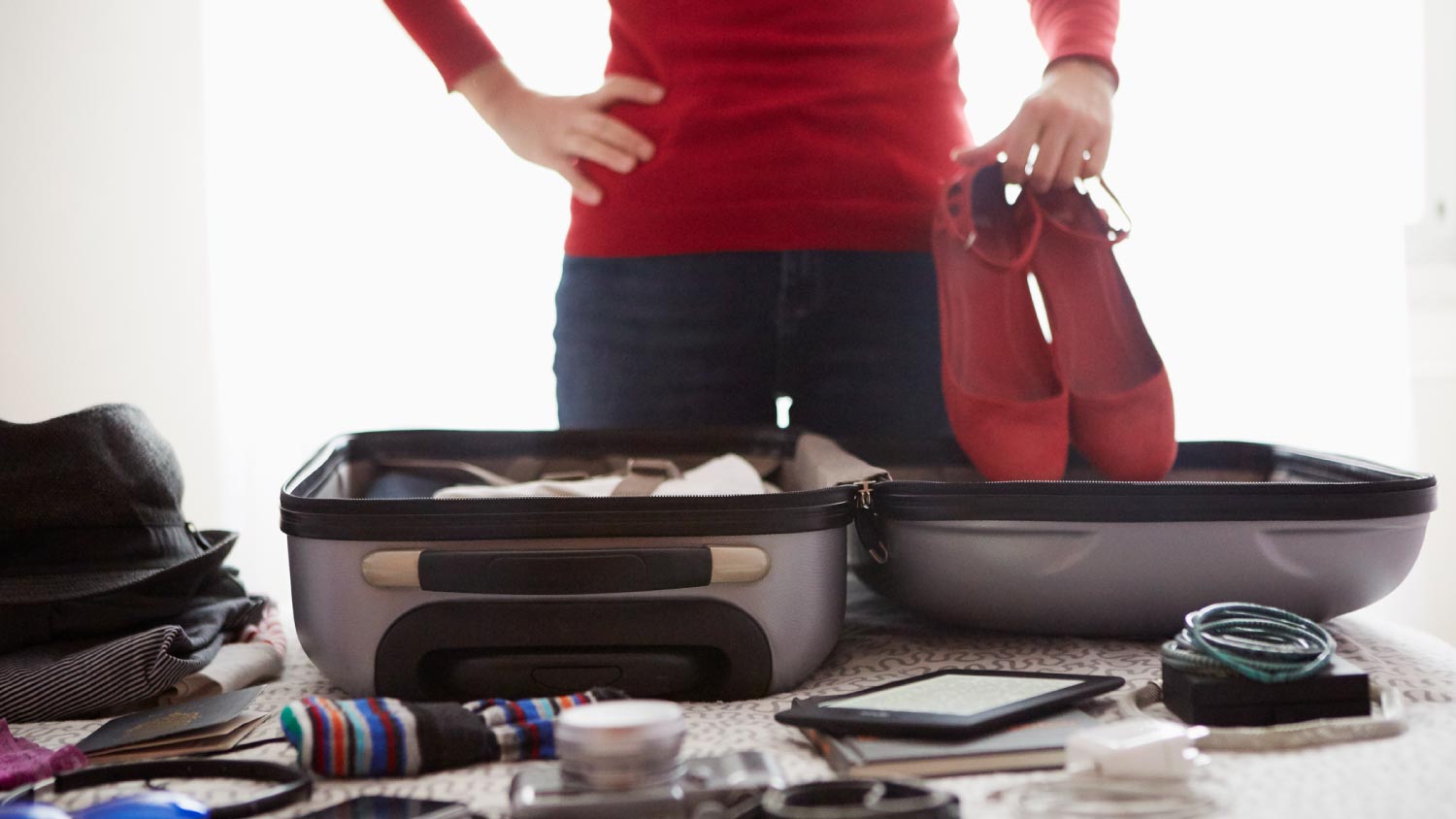 A woman packing suitcase and holding shoes