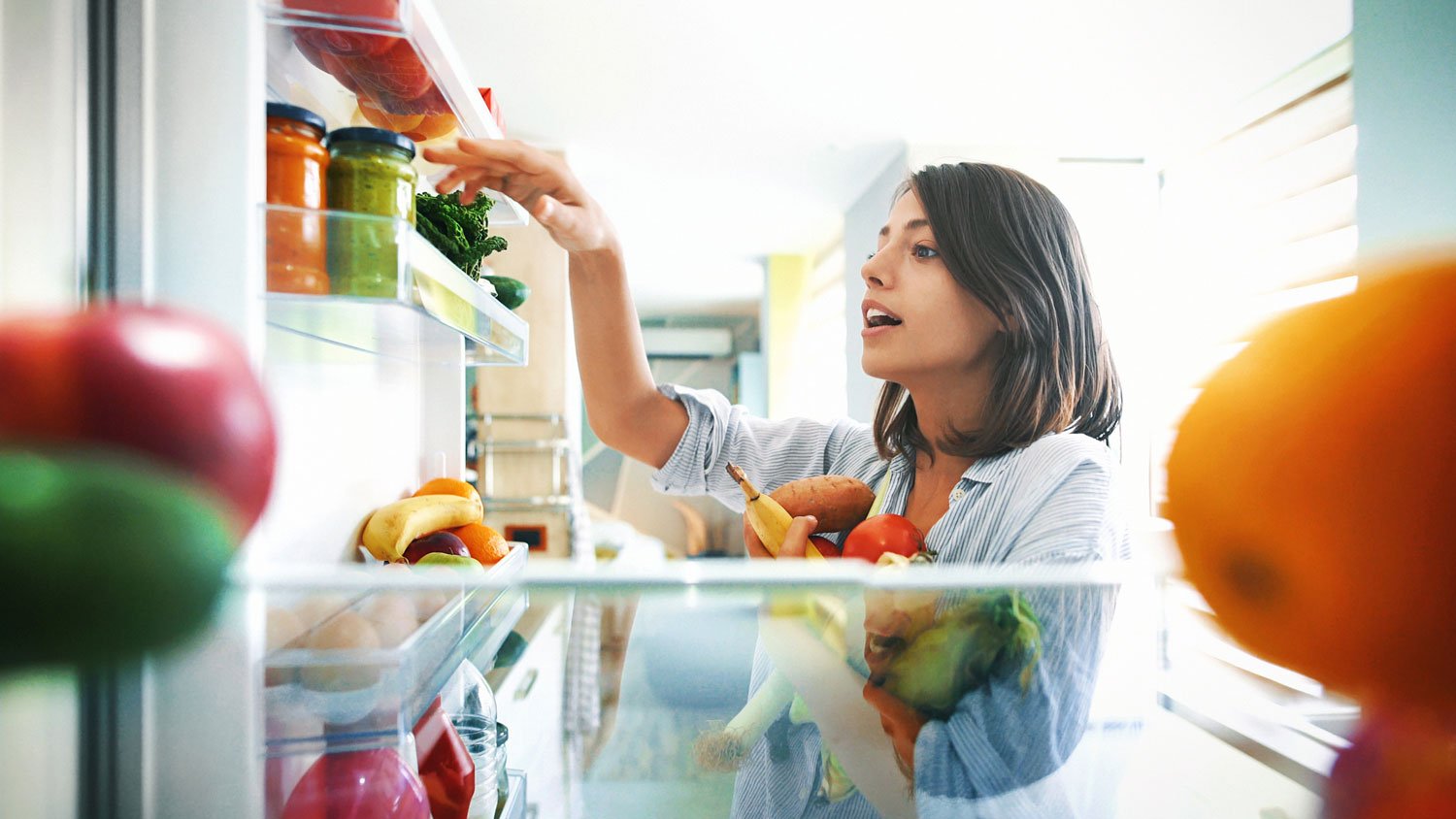 A woman picking vegetables from the refrigerator