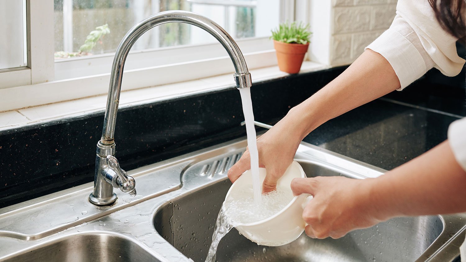 Woman rinsing a bowl in kitchen sink