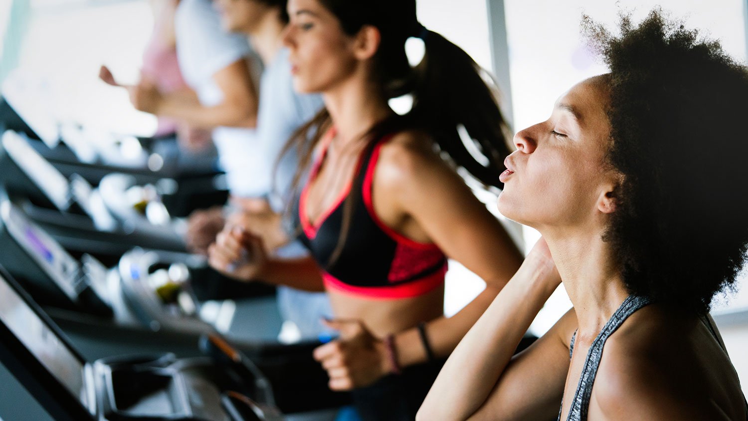 Woman running on a treadmill at a crowded gym