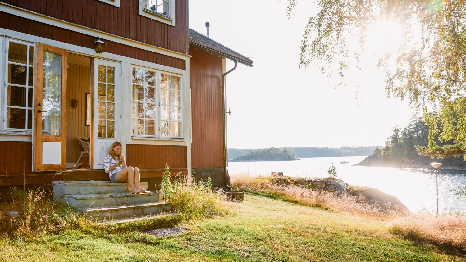 A woman sitting on steps in doorway of log cabin