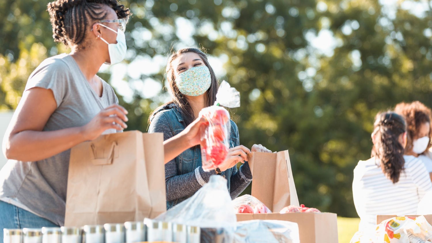 two women wearing masks working a food drive