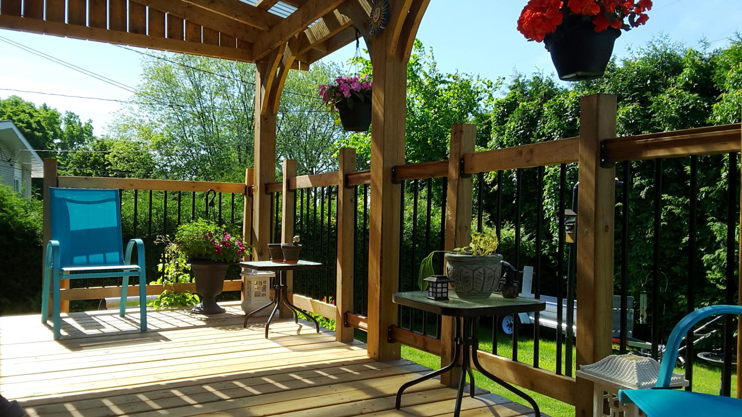 A wooden deck with a roof overlooking the backyard of a house