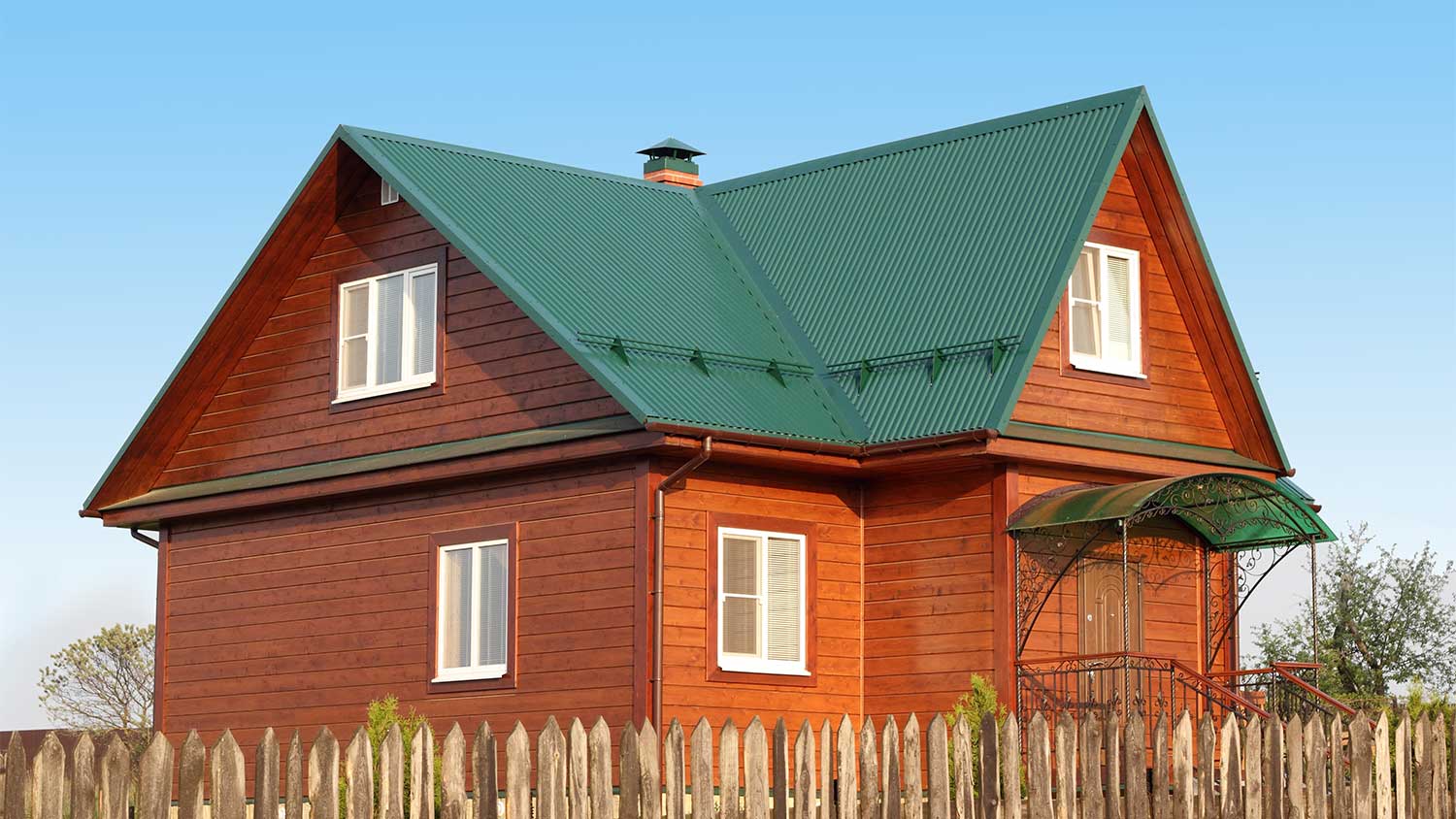 Wooden country house with green metal roof