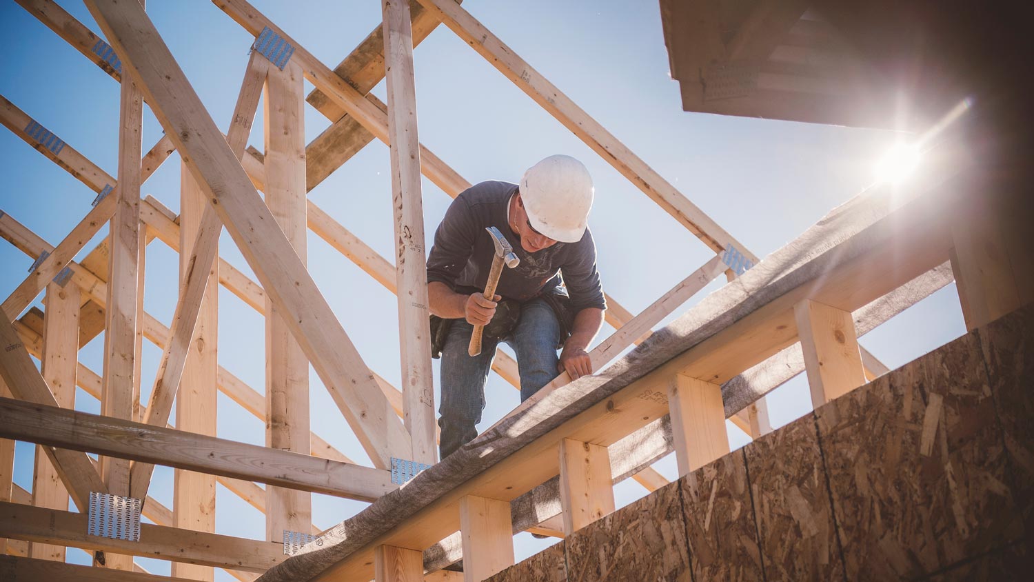 A worker building a wooden house frame