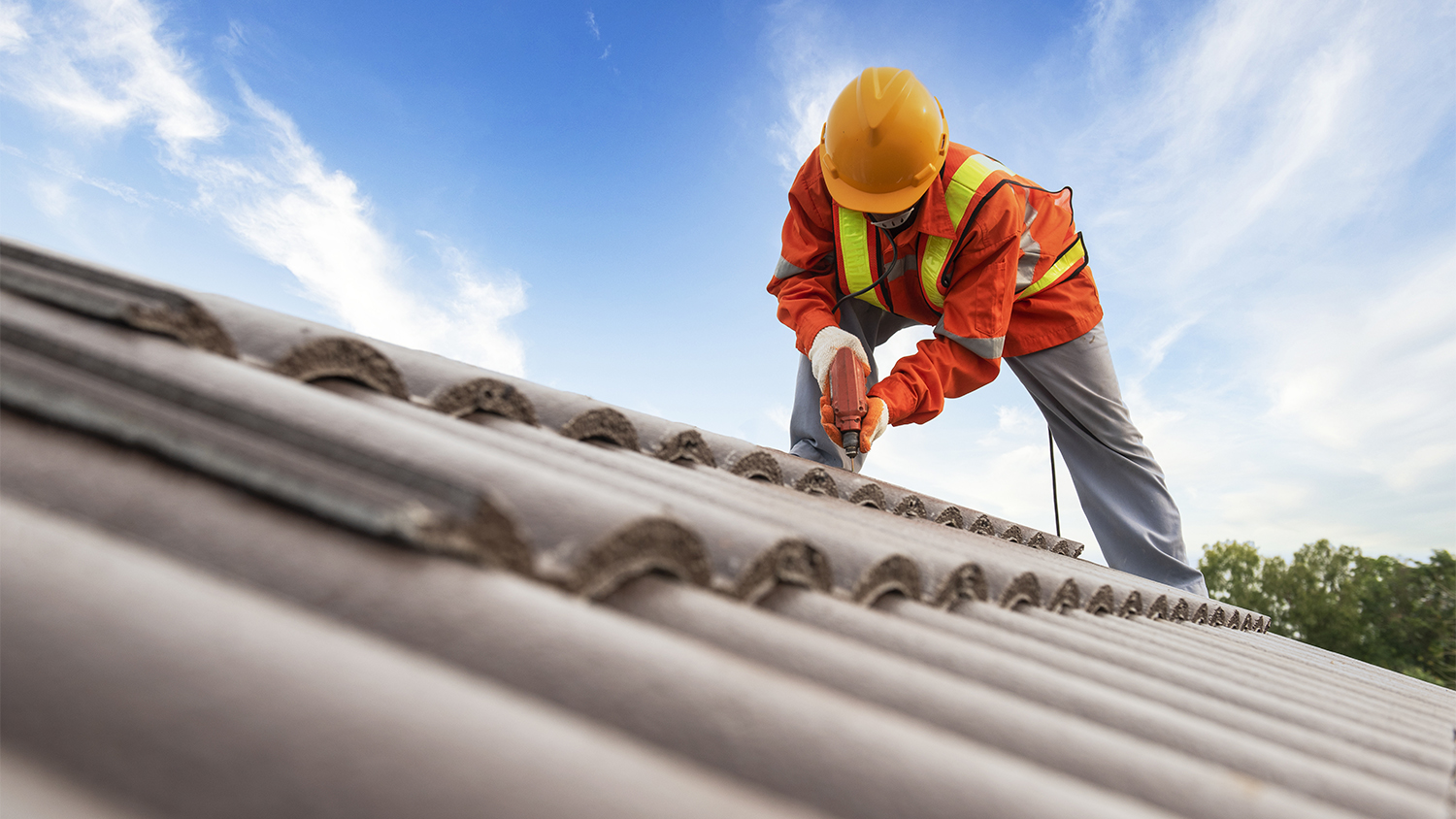 worker drilling on roof